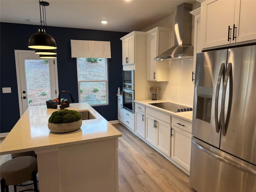 Modern kitchen featuring white shaker cabinets, stainless steel appliances, quartz island with sink in Davidson Homes The Hartwell A, Canton, GA