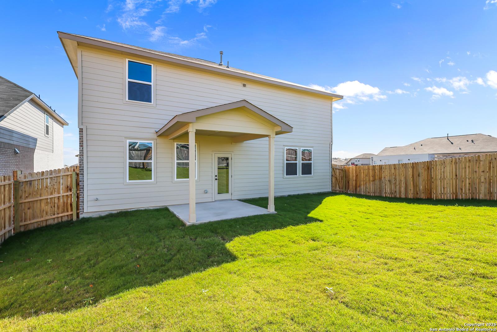 Covered back patio with sliding doors overlooking fenced green yard in two-story Davidson Homes The Douglas E, Comanche Ridge, San Antonio