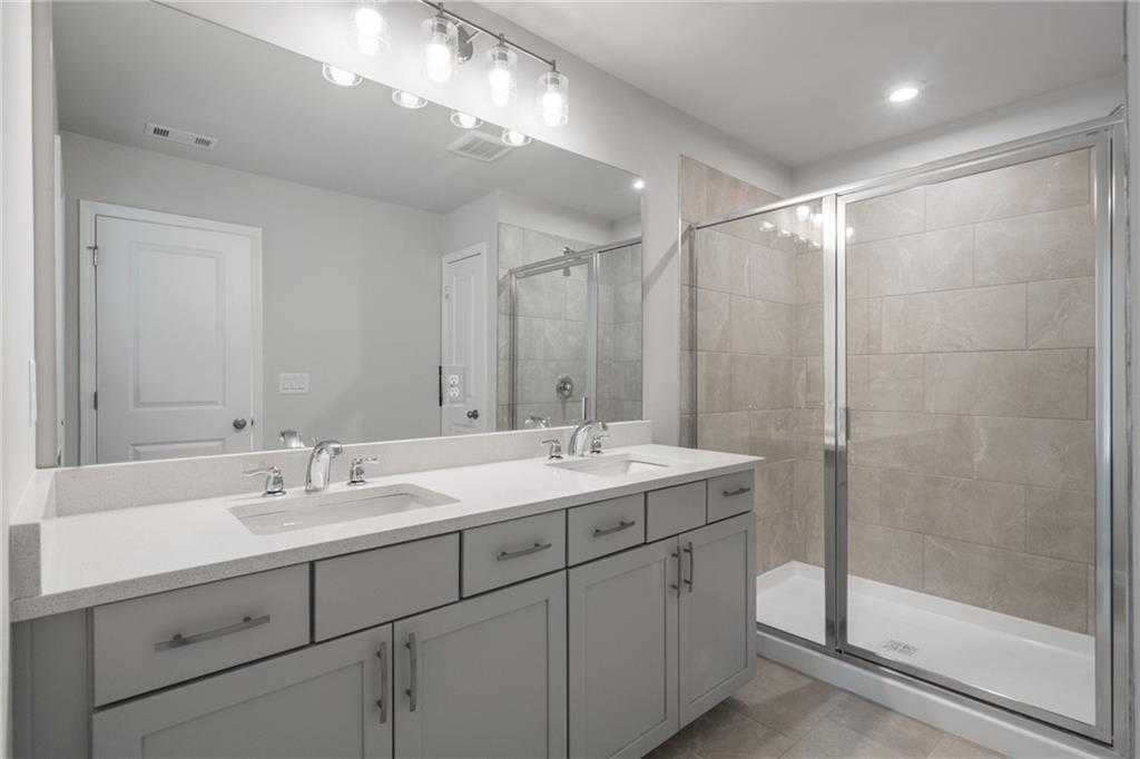 Modern master bathroom with double vanity, quartz counters, frameless glass shower in Davidson Homes The Cary A, Kennesaw, GA