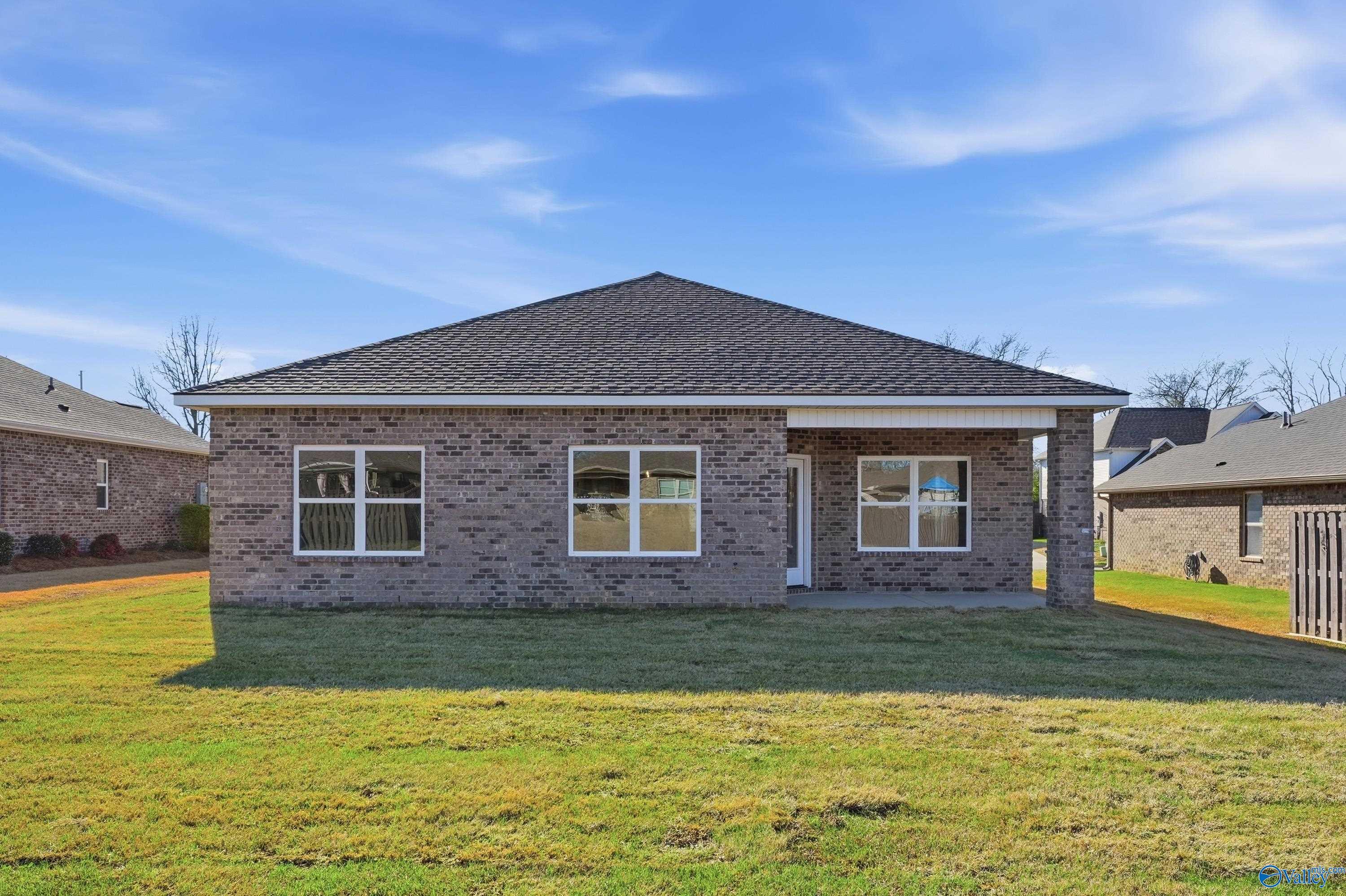 Single-story brick home with gabled roof, white-trimmed windows, covered porch, and lush green yard in Flint Meadows, New Market, Alabama
