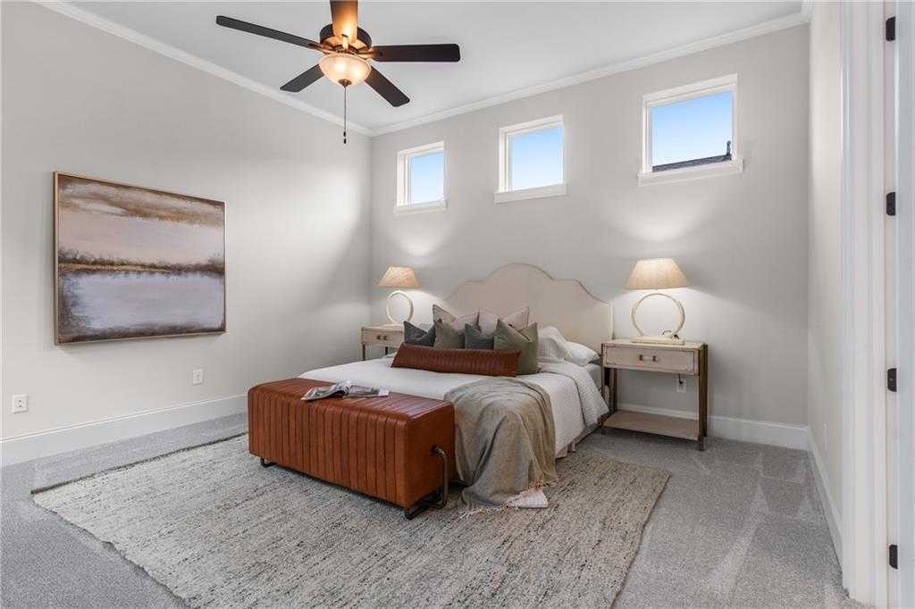 Elegant master bedroom with ceiling fan, tufted bed, abstract art, and soft lamps in Davidson Homes The Seaside B, Woodstock, GA