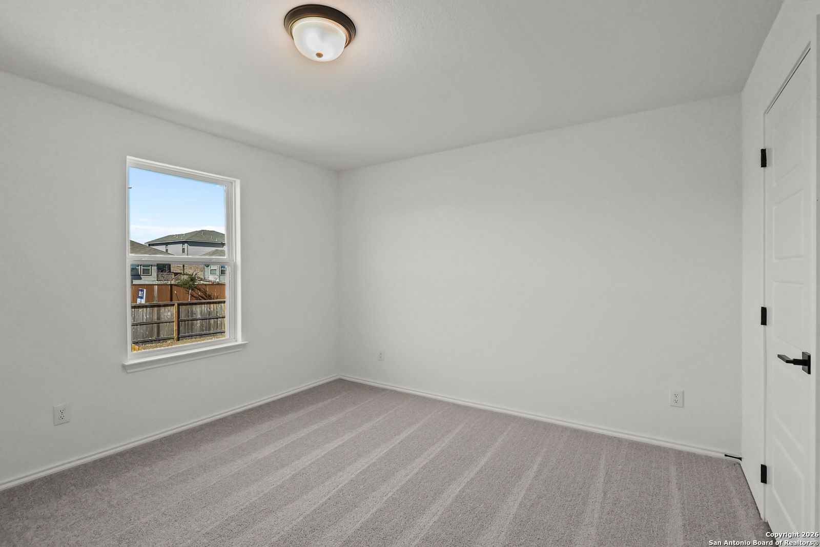 Bright secondary bedroom with large window overlooking backyard, gray carpet in Davidson Homes The Douglas E, San Antonio
