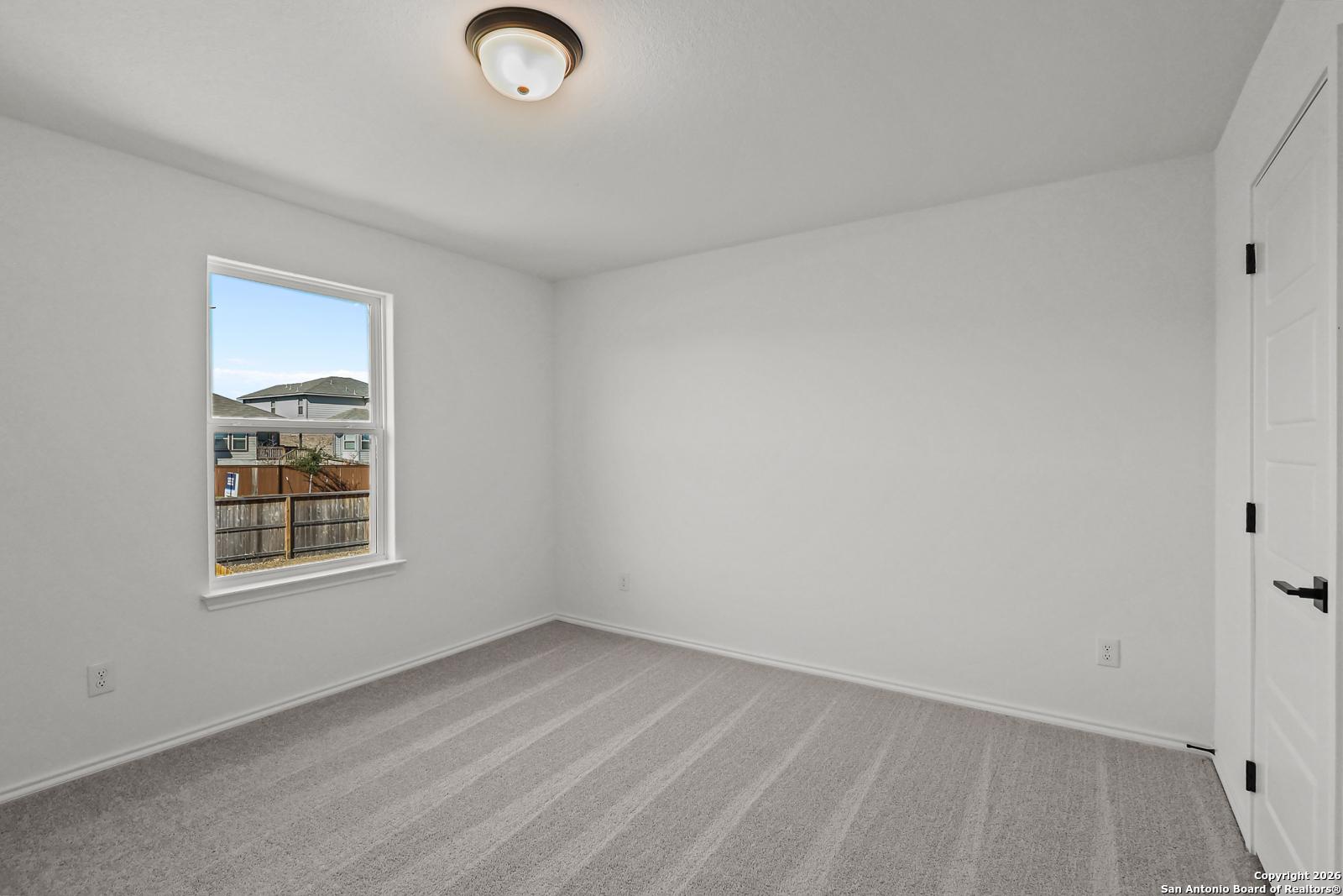 Bright secondary bedroom with large window overlooking backyard, gray carpet in Davidson Homes The Douglas E, San Antonio