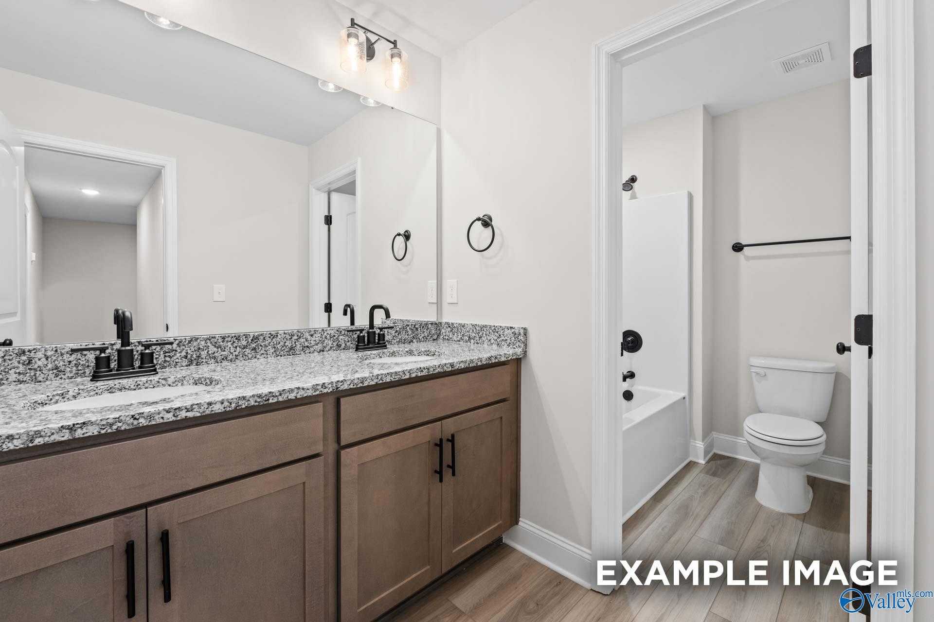 Modern master bathroom with double granite vanity, soaking tub, and neutral tones in Davidson Homes The Camden D, Huntsville