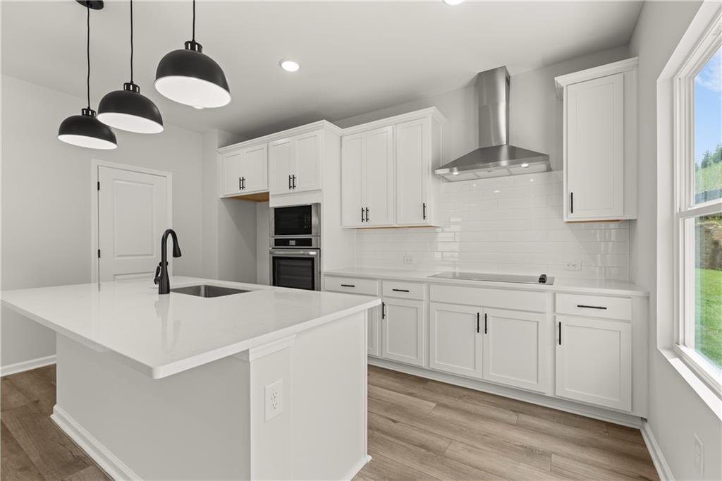 Modern kitchen with white cabinets, quartz island, and stainless steel appliances in The Hartwell A, The Bluffs, Canton.