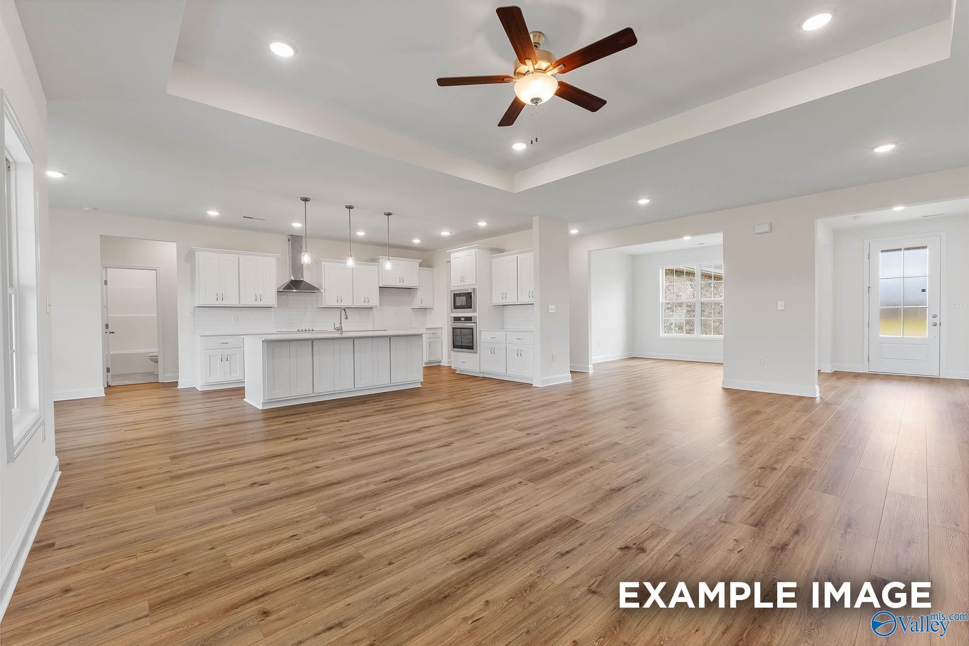 Open-concept kitchen-living space with hardwood floors, white island cabinets, ceiling fan, and recessed lighting in Davidson Homes The Emory, Toney, AL