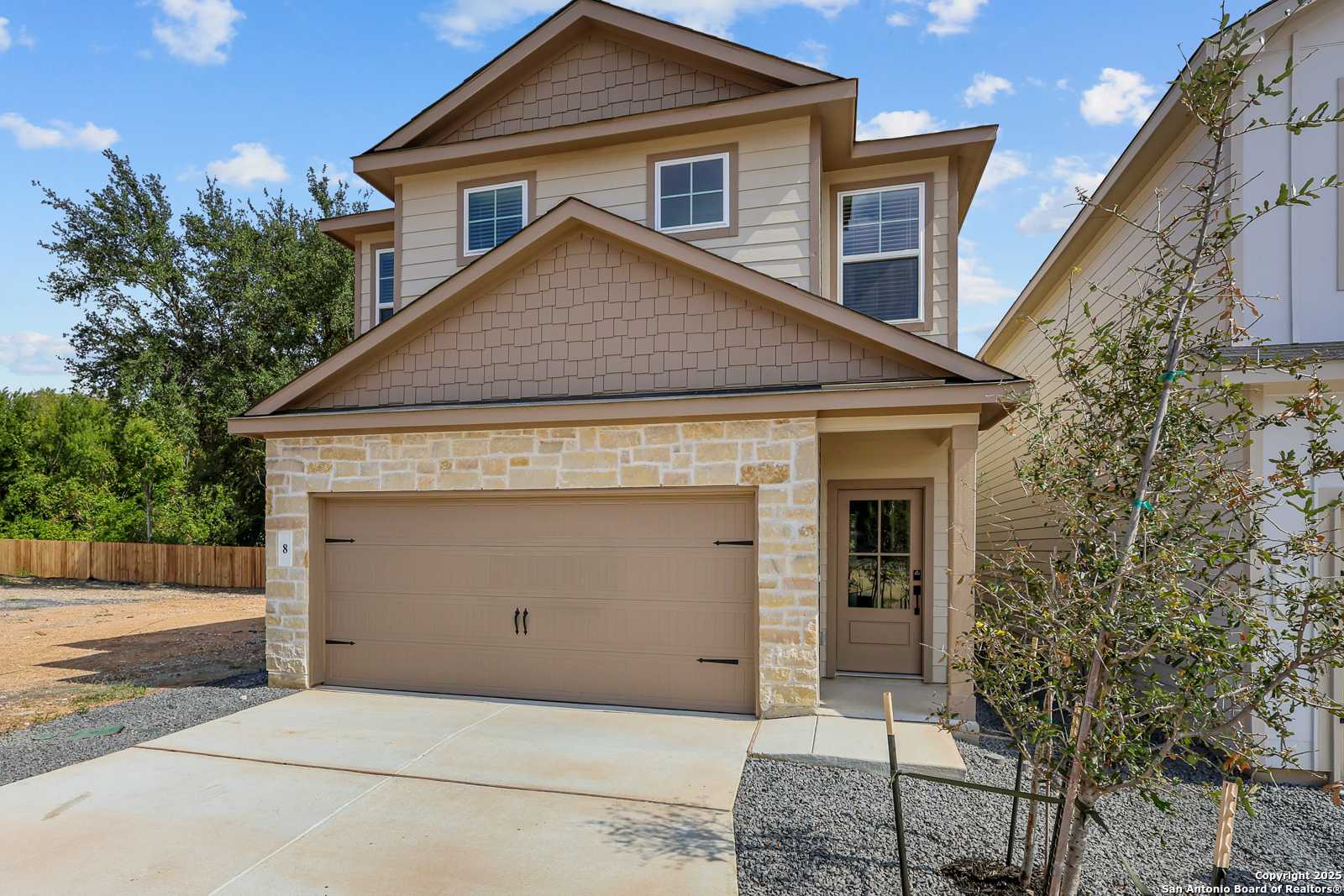 Two-story beige Davidson Homes Charlotte B with 2-car garage, stone accents, and driveway in Cedar Heights, San Antonio, Texas