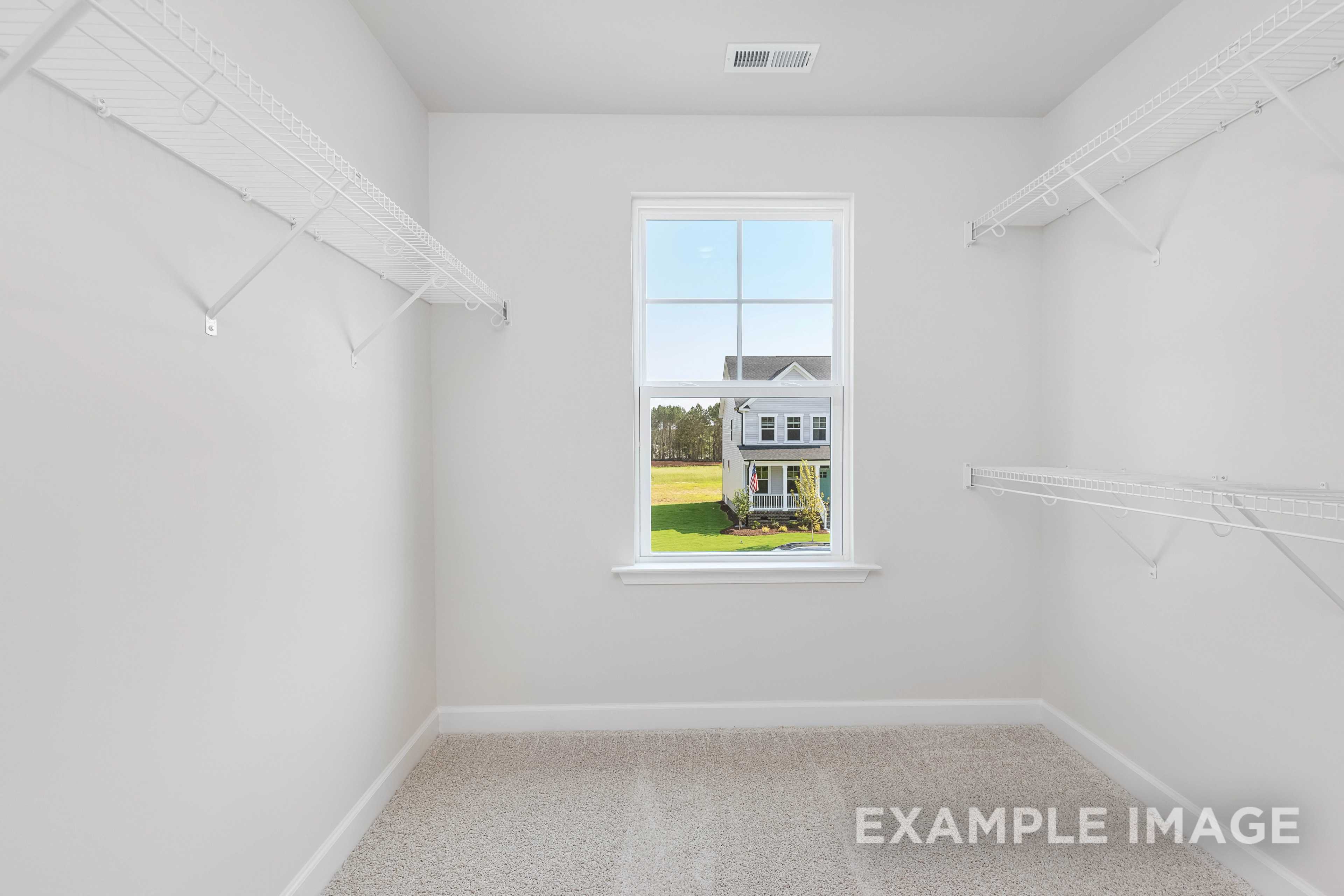 Spacious walk-in closet in The Willow B master suite featuring white shelving, rods, and window overlooking green lawn and home