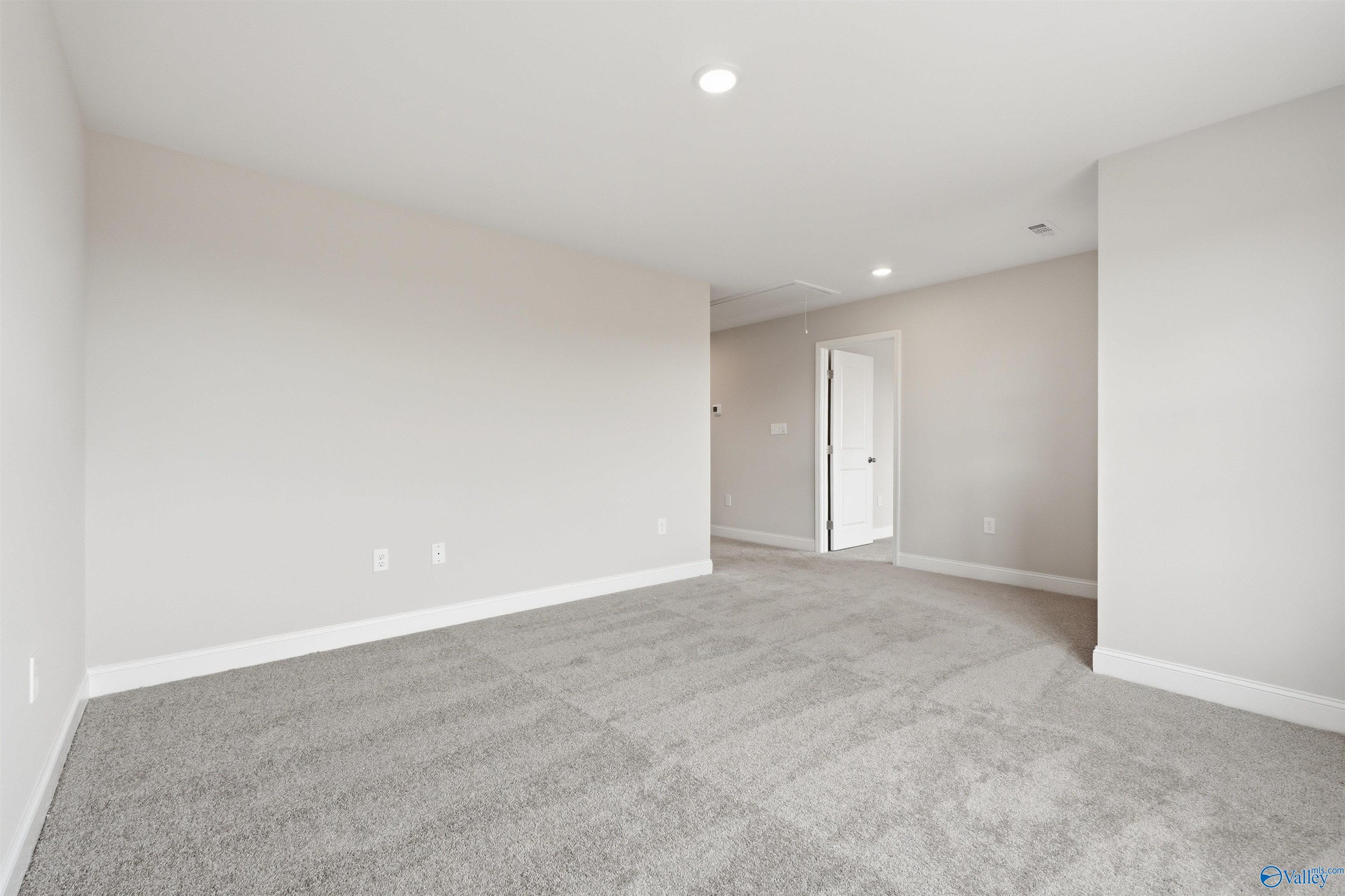 Spacious, carpeted bedroom with neutral walls in The Shelby D floor plan by Davidson Homes in Evergreen Mill, Madison, AL.