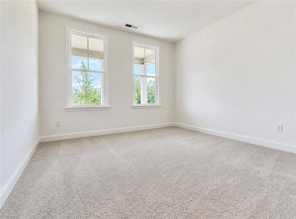 Bright, carpeted bedroom with large windows in The Hickory C floor plan by Davidson Homes in Wehunt Meadows, Hoschton, GA.