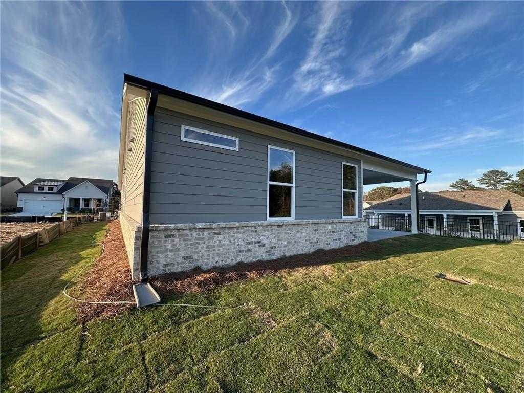 Modern gray-sided single-story home with brick accents, large windows, and covered patio in Kelly Preserve, Loganville, GA