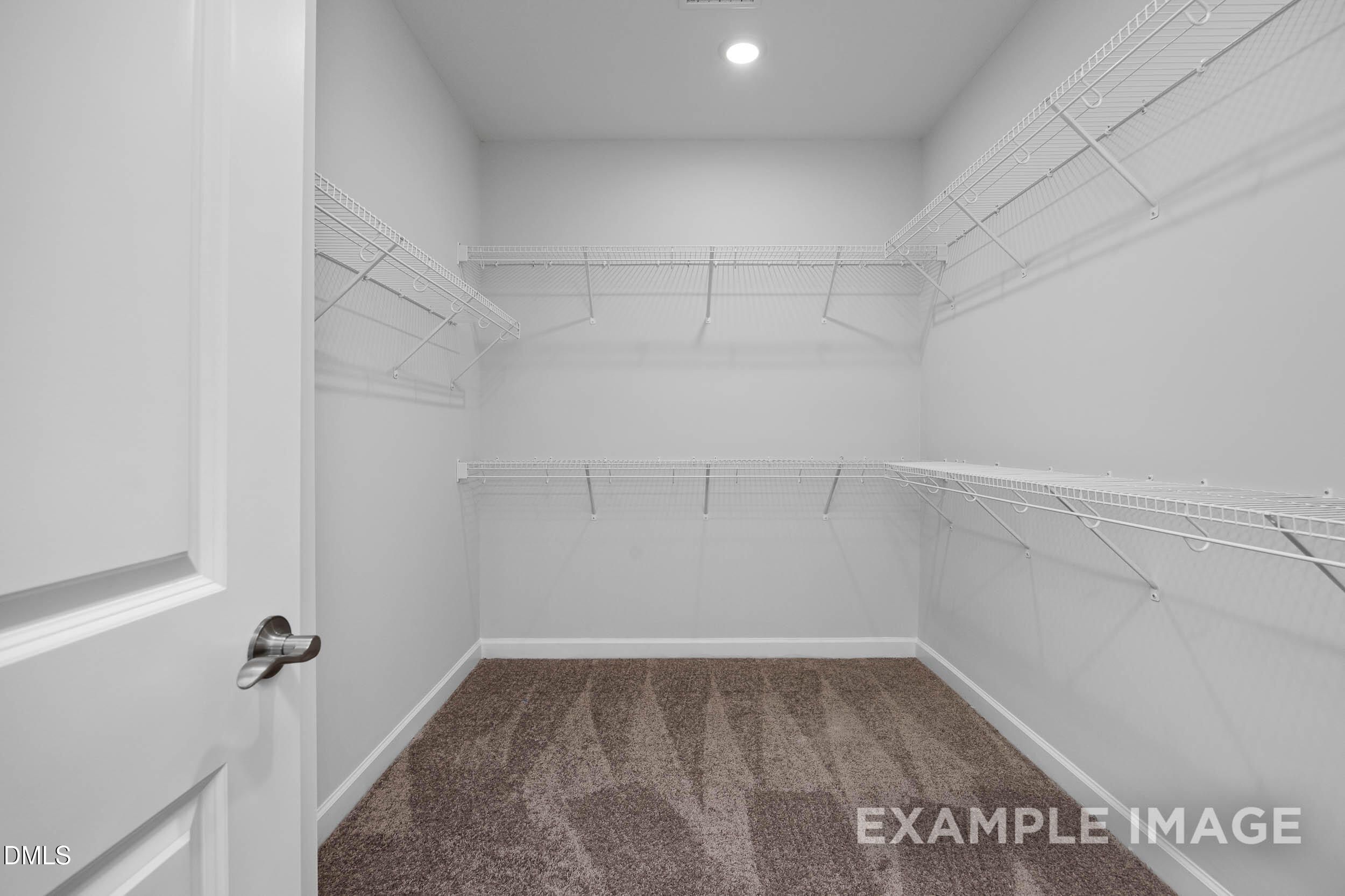 Spacious walk-in closet with white wire shelving and patterned carpet in Davidson Homes The Ash B, Lillington, NC