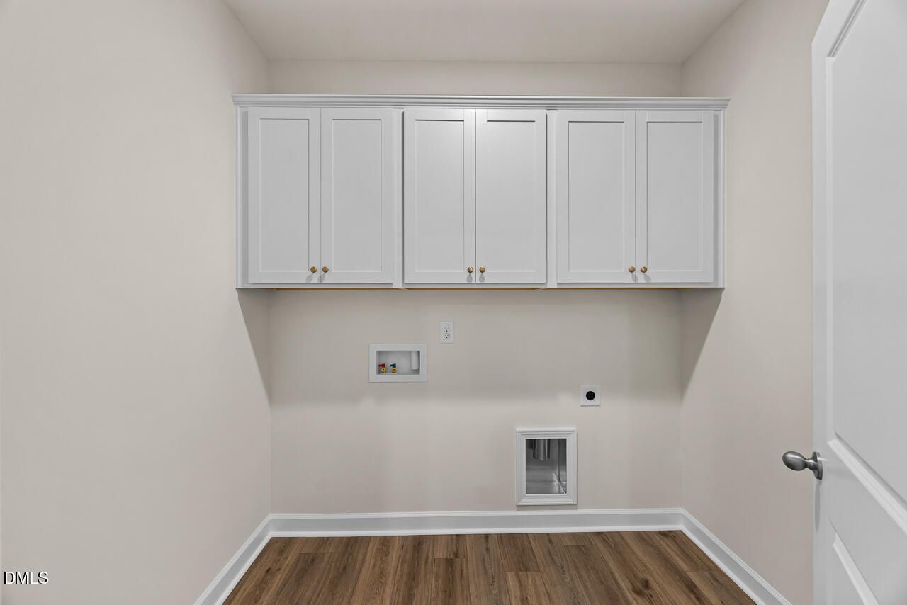 Laundry room with white shaker cabinets, wood-look flooring, and washer connections in Davidson Homes The Birch II C, Wake Forest, NC