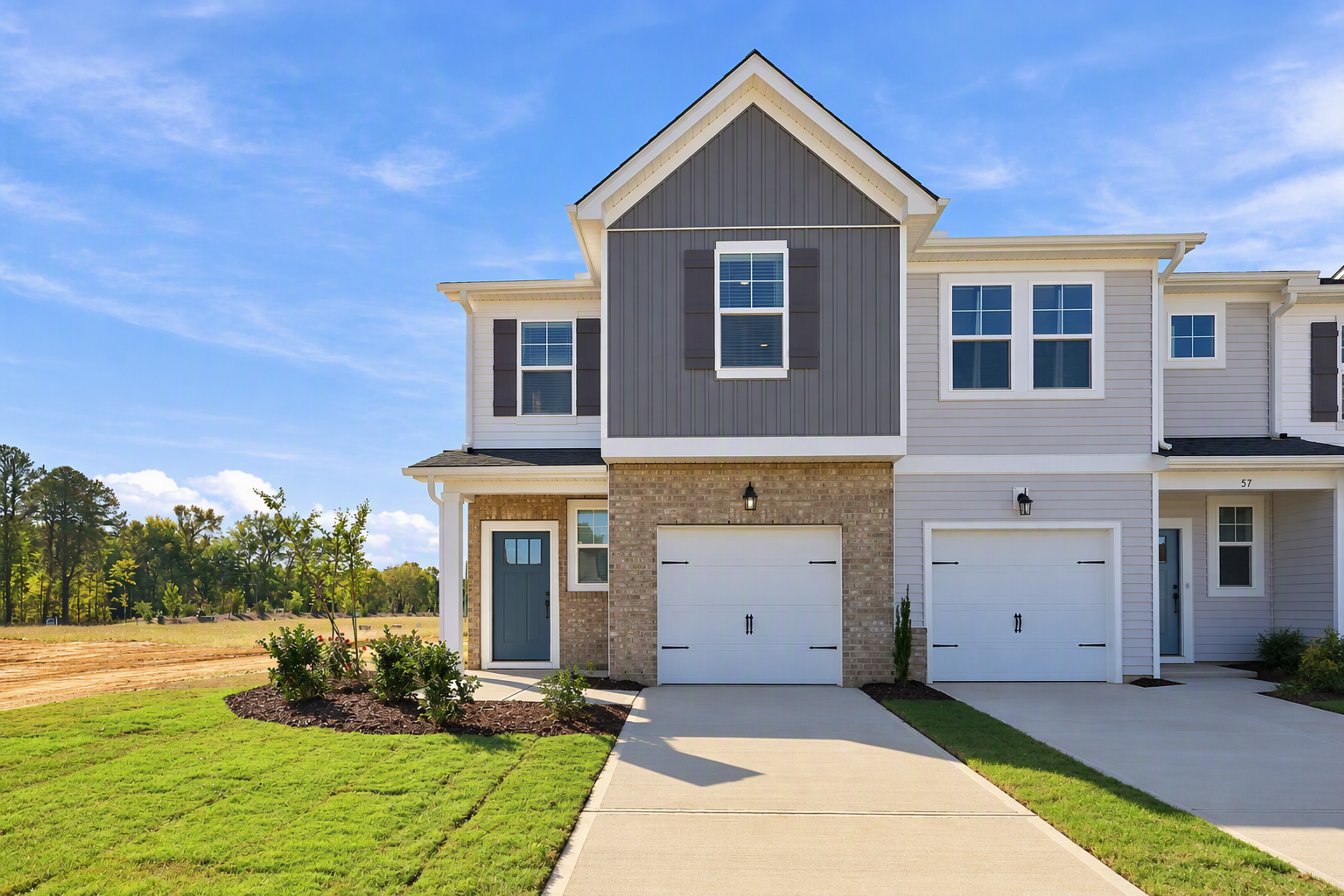 Two-story townhouse exterior at Townes at North Main in Lillington, NC with attached garages, blue front door, and landscaped lawn