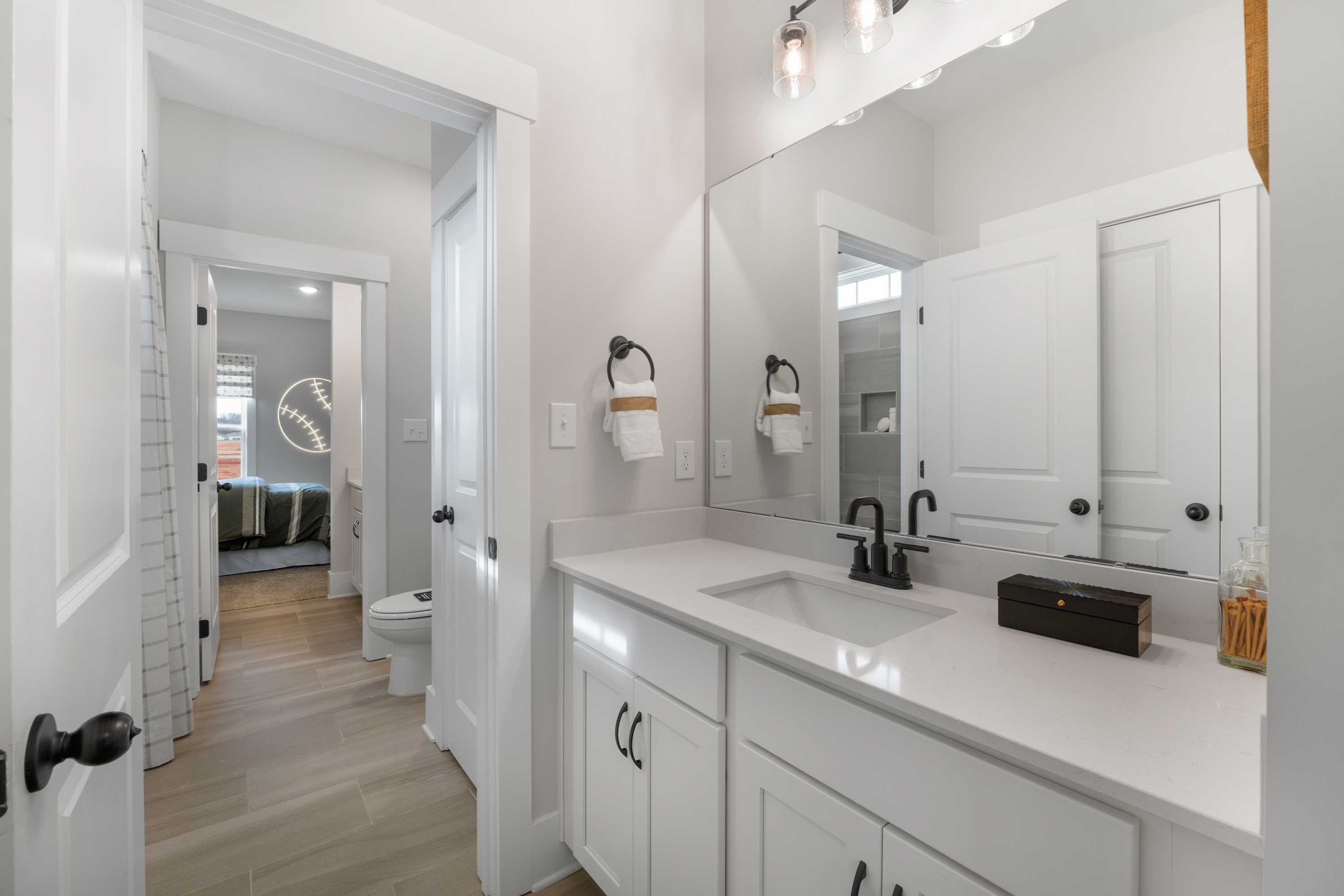 Spacious modern bathroom in Briercreek by Davidson Homes, Meridianville AL with white shaker vanity, quartz sink, and hardwood floors