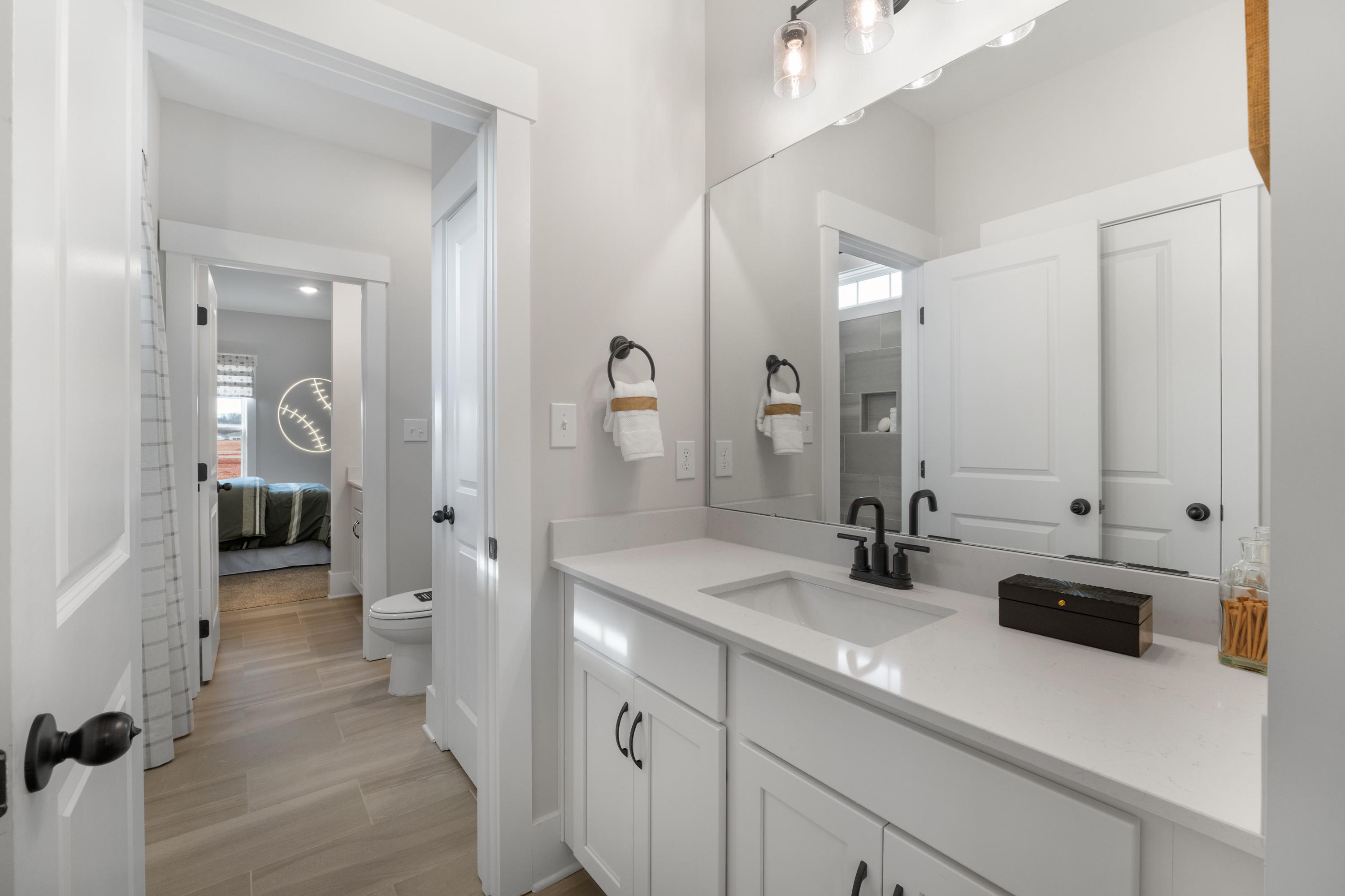 Spacious modern bathroom in Briercreek by Davidson Homes, Meridianville AL with white shaker vanity, quartz sink, and hardwood floors