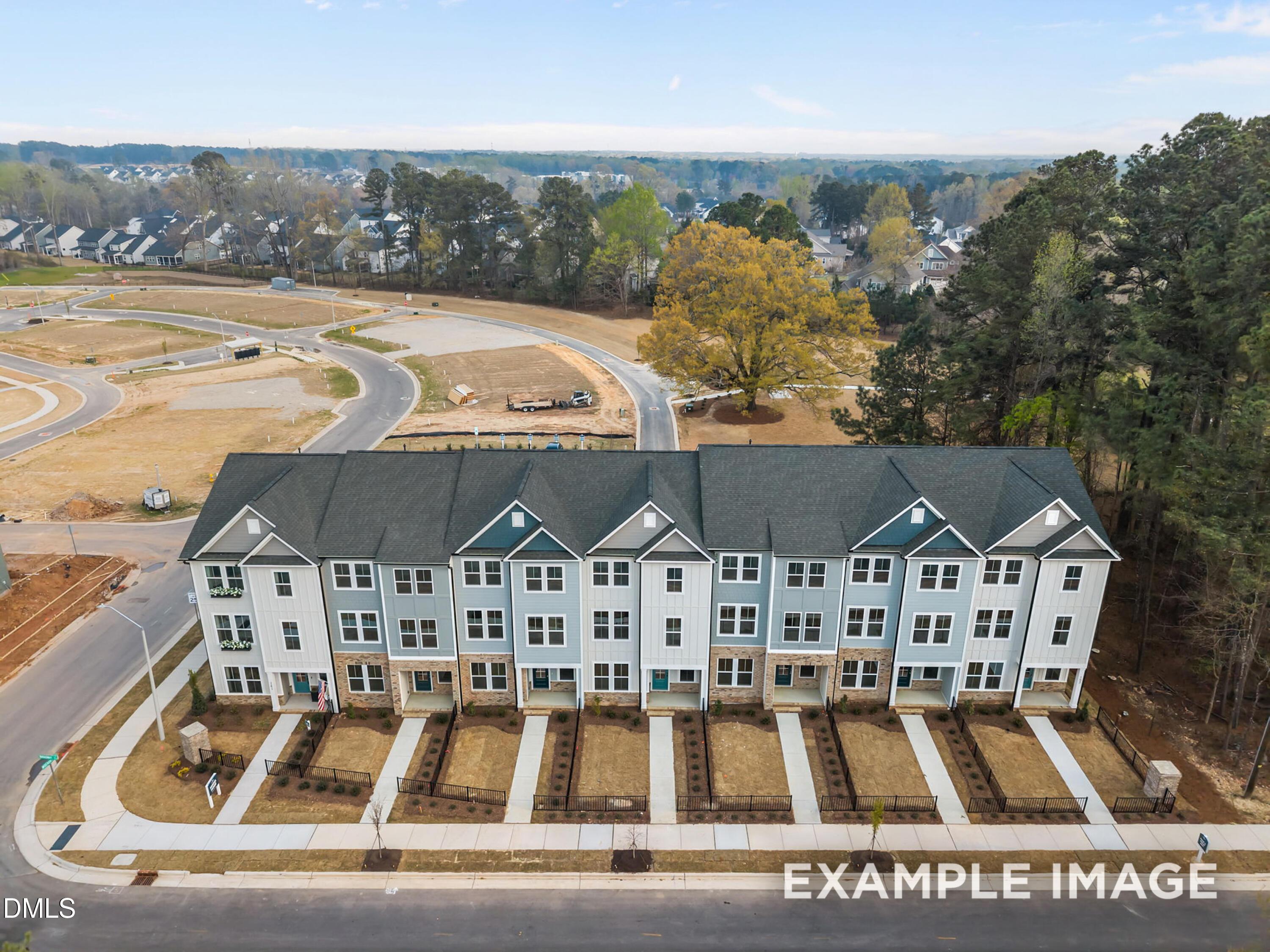 Aerial view of row of modern 3-story The Mitchell townhomes with blue-white siding, garages in Camden Park, Knightdale, NC by Davidson Homes