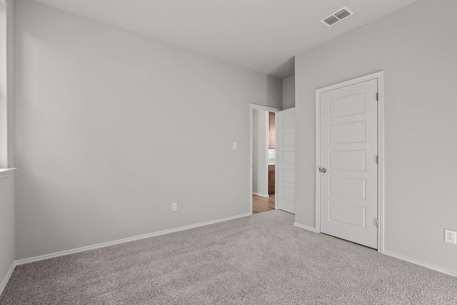 Spacious bedroom with neutral carpet and closet in The Frio G floor plan at Davidson Homes in Heartland, Texas.