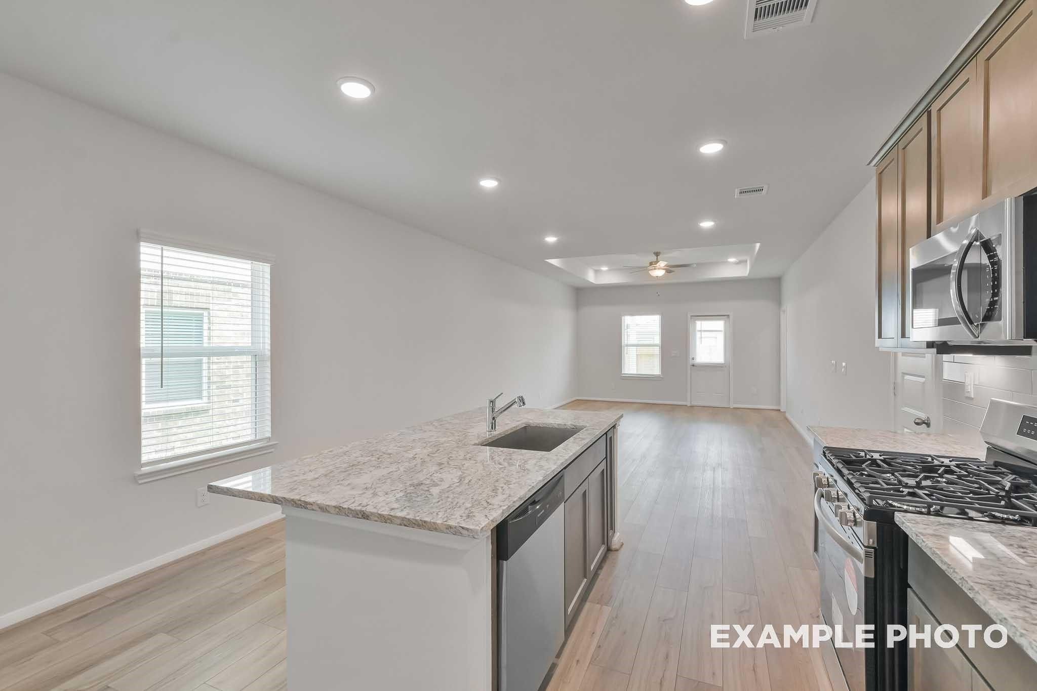 Modern kitchen island with granite countertop, stainless steel sink, dishwasher in The Frio F floor plan, Conroe, Texas