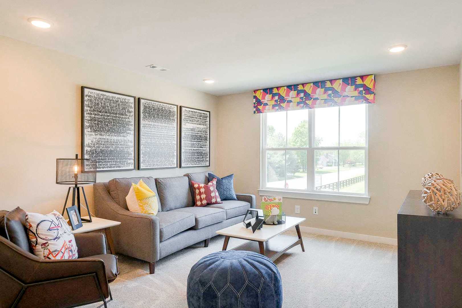 Cozy family room at The Meadows in Smyrna TN with gray sectional sofa, colorful pillows, toys on coffee table, and large window