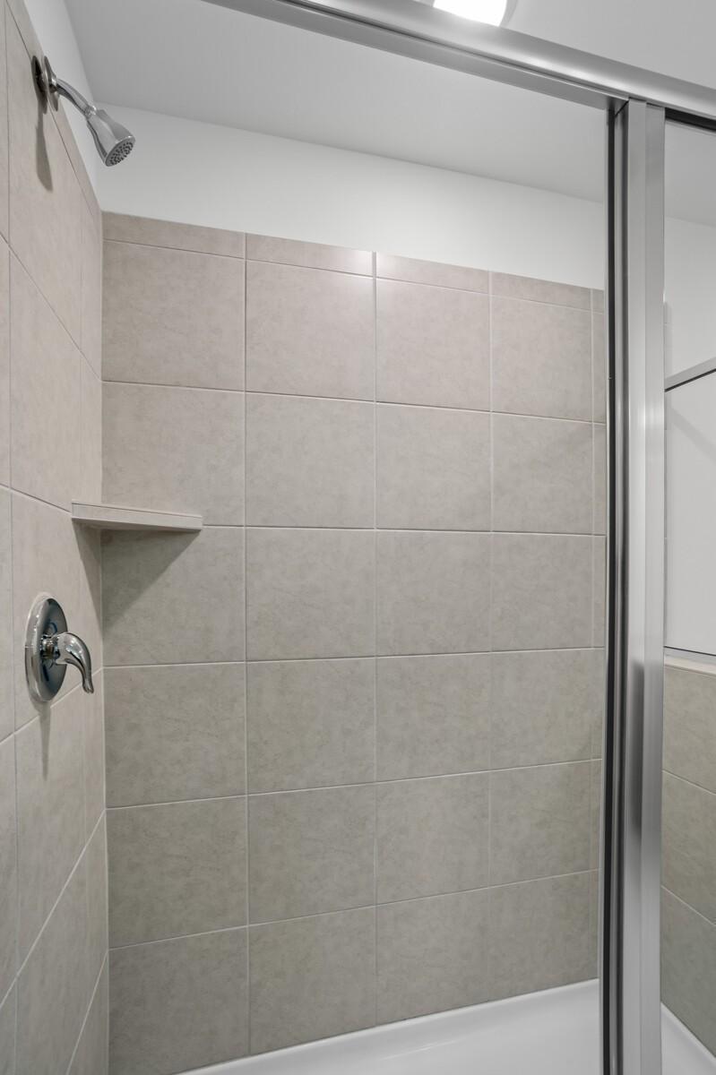 Modern tiled walk-in shower with glass door and built-in shelf in The Logan C master bath, Davidson Homes, White House, TN