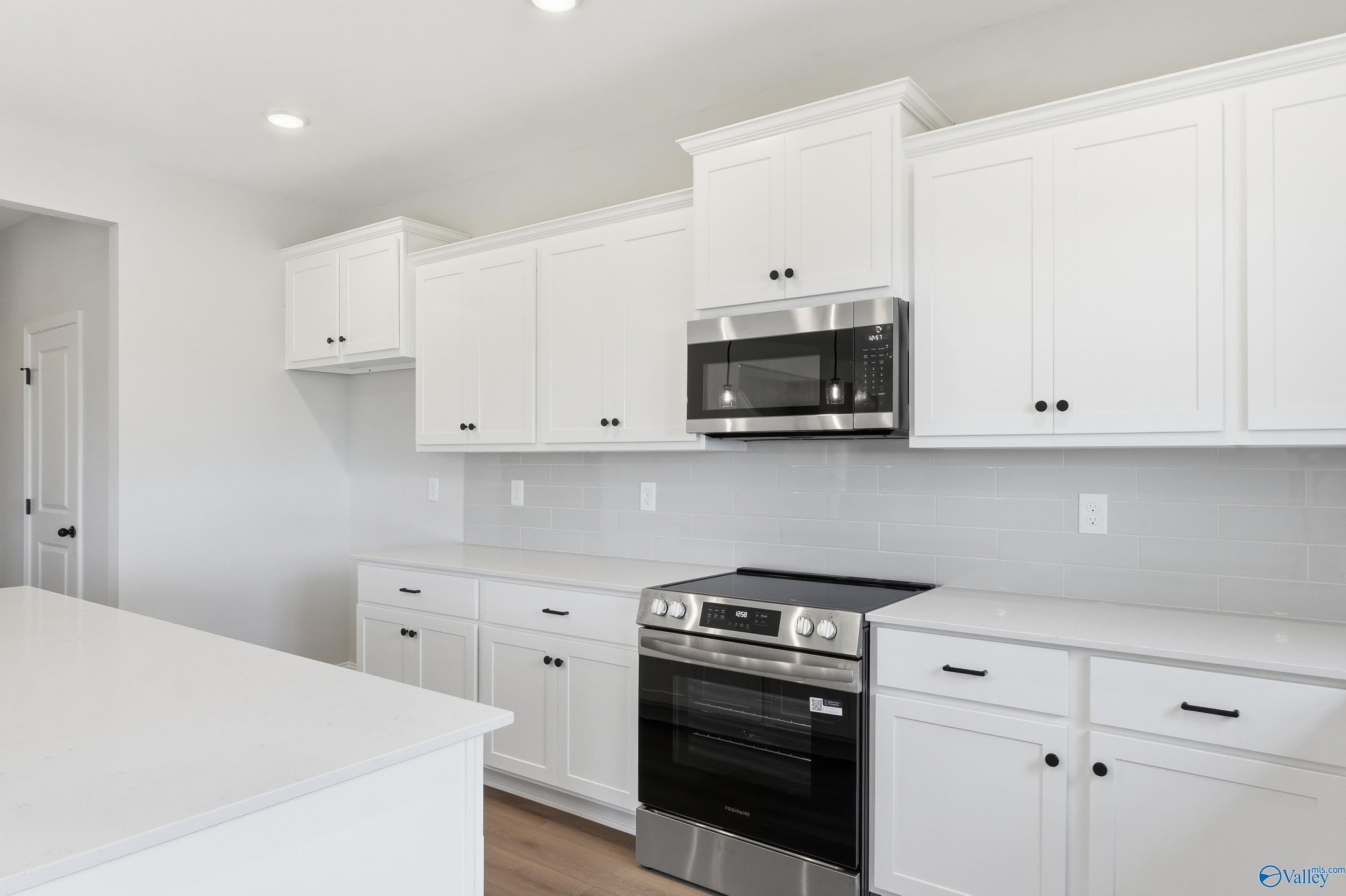 Modern white kitchen with stainless steel appliances, subway tile backsplash in Davidson Homes Chelsea D, Cullman, Alabama