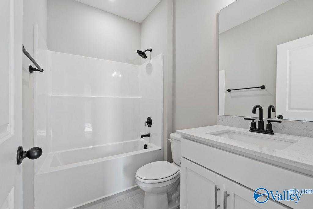 Modern secondary bathroom with white tub-shower combo, vanity, and mirror in Davidson Homes The Montgomery B, Hartselle, AL