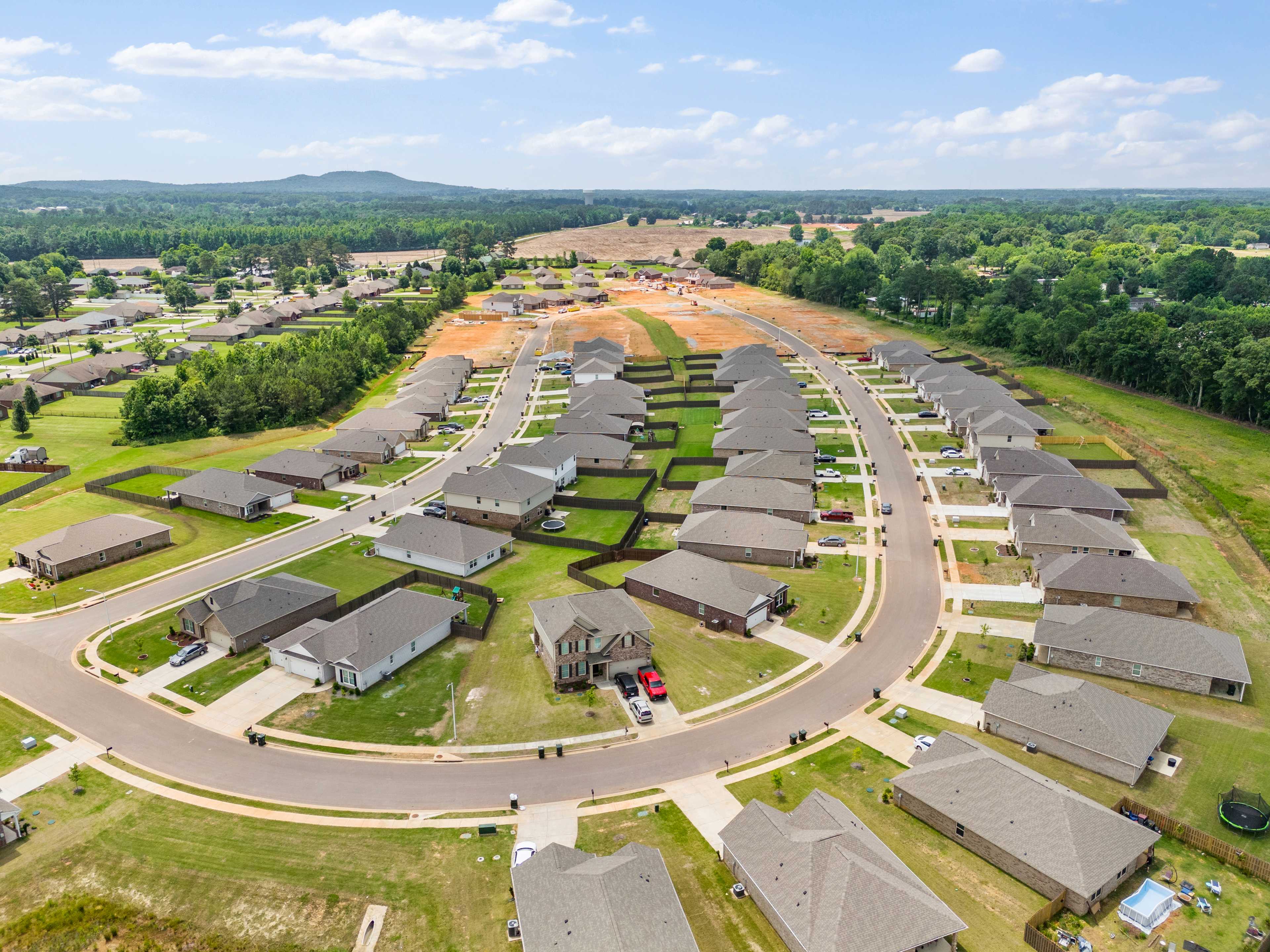 Aerial view of new homes under construction in Durham Farms, Harvest Alabama, with curved streets and wooded surroundings