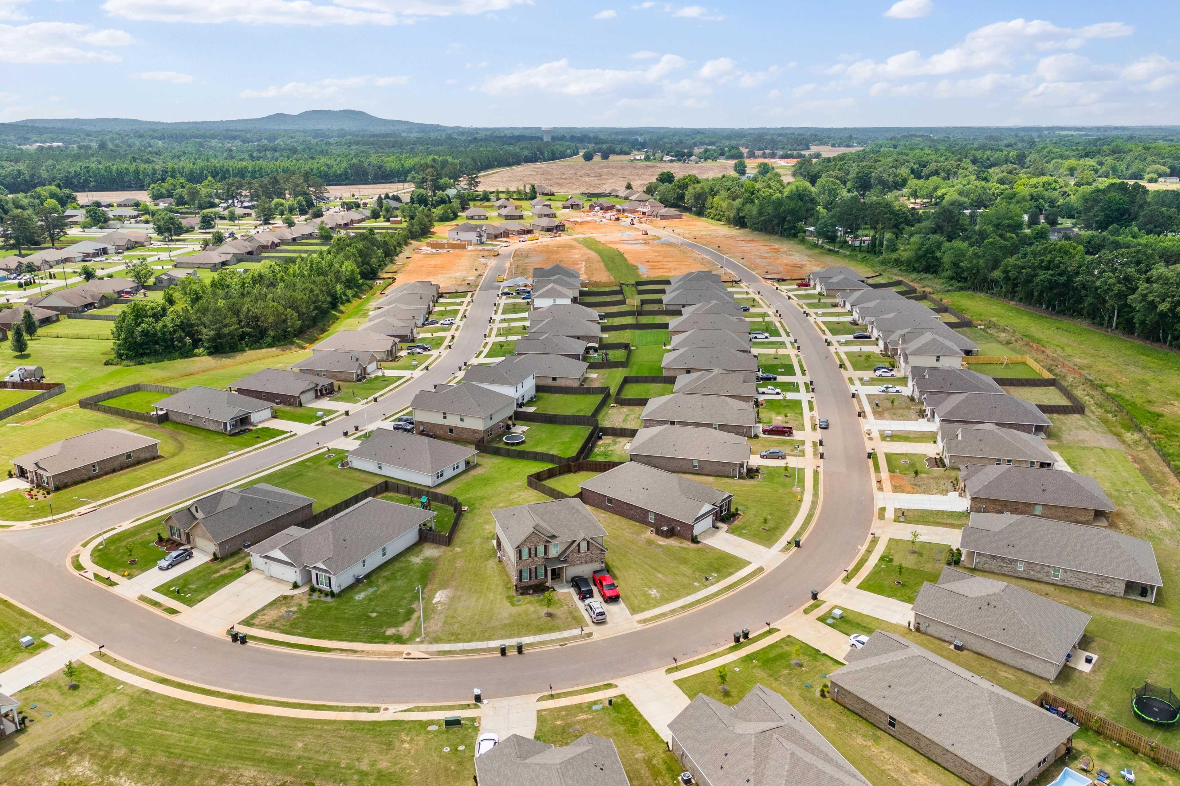 Aerial view of new single-family homes in Durham Farms, Harvest Alabama by Davidson Homes with curved streets and wooded backdrop