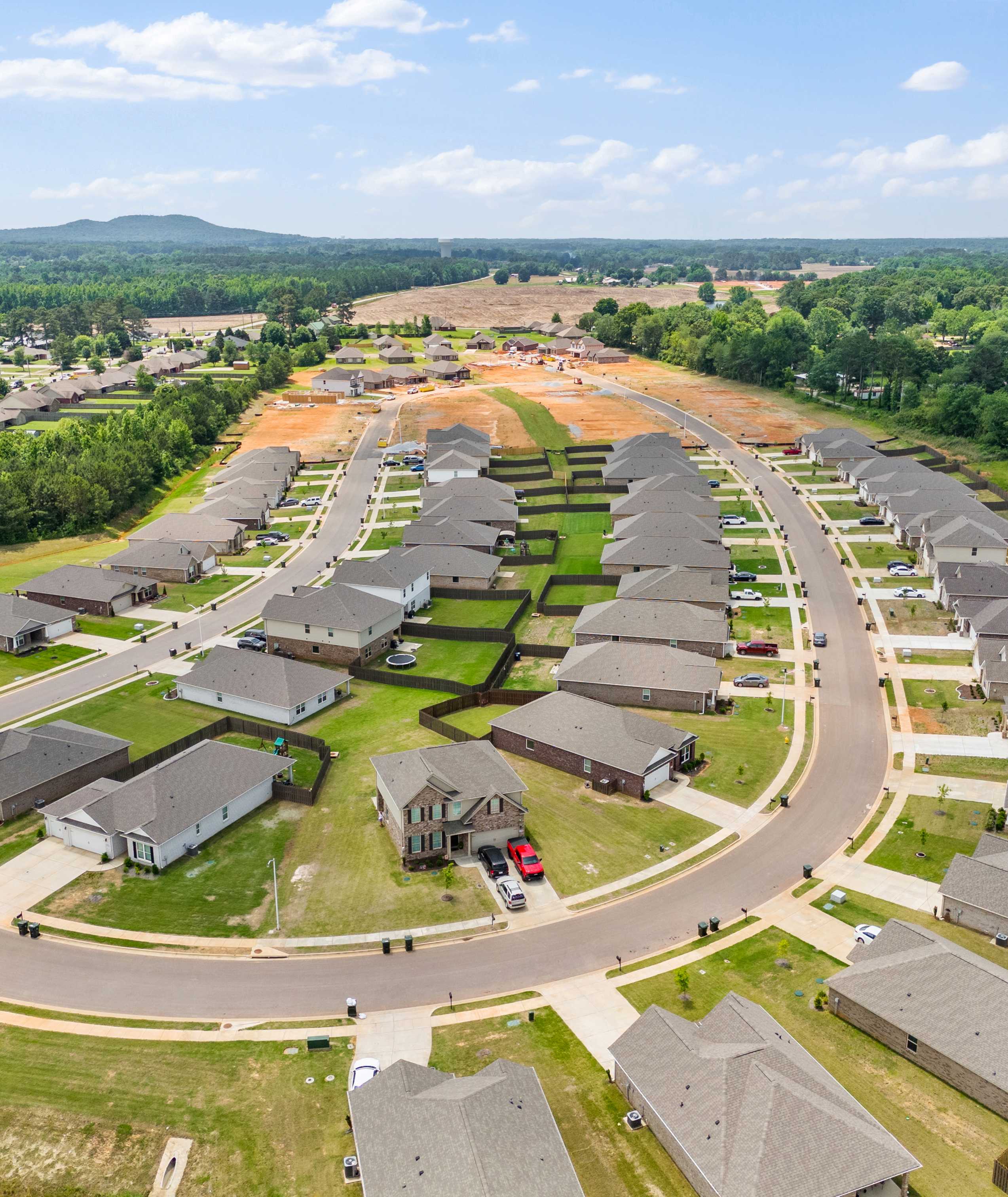 Aerial view of new homes under construction in Durham Farms, Harvest Alabama, with curved streets and wooded surroundings