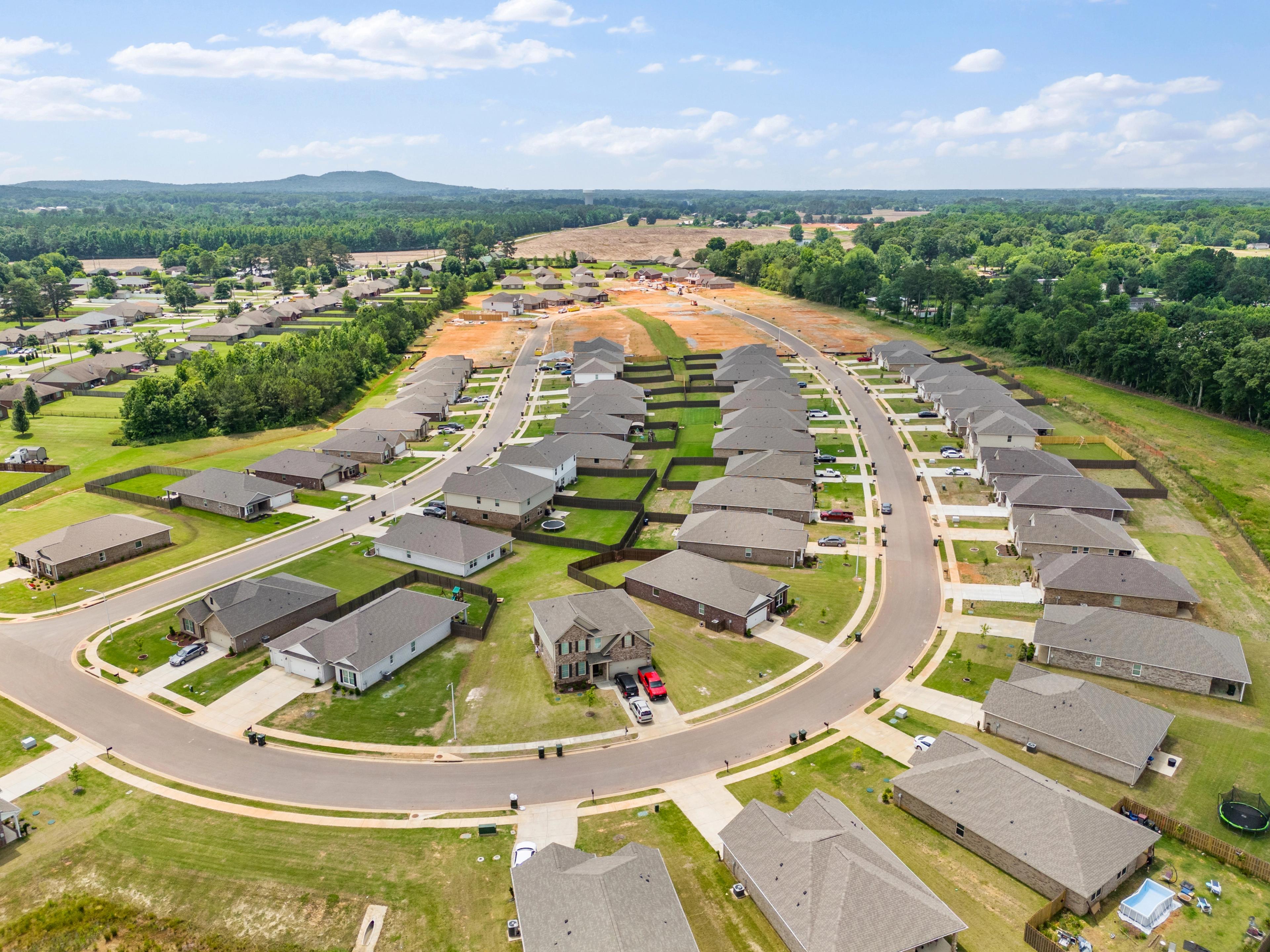 Aerial view of new homes under construction in Durham Farms, Harvest Alabama, with curved streets and wooded surroundings