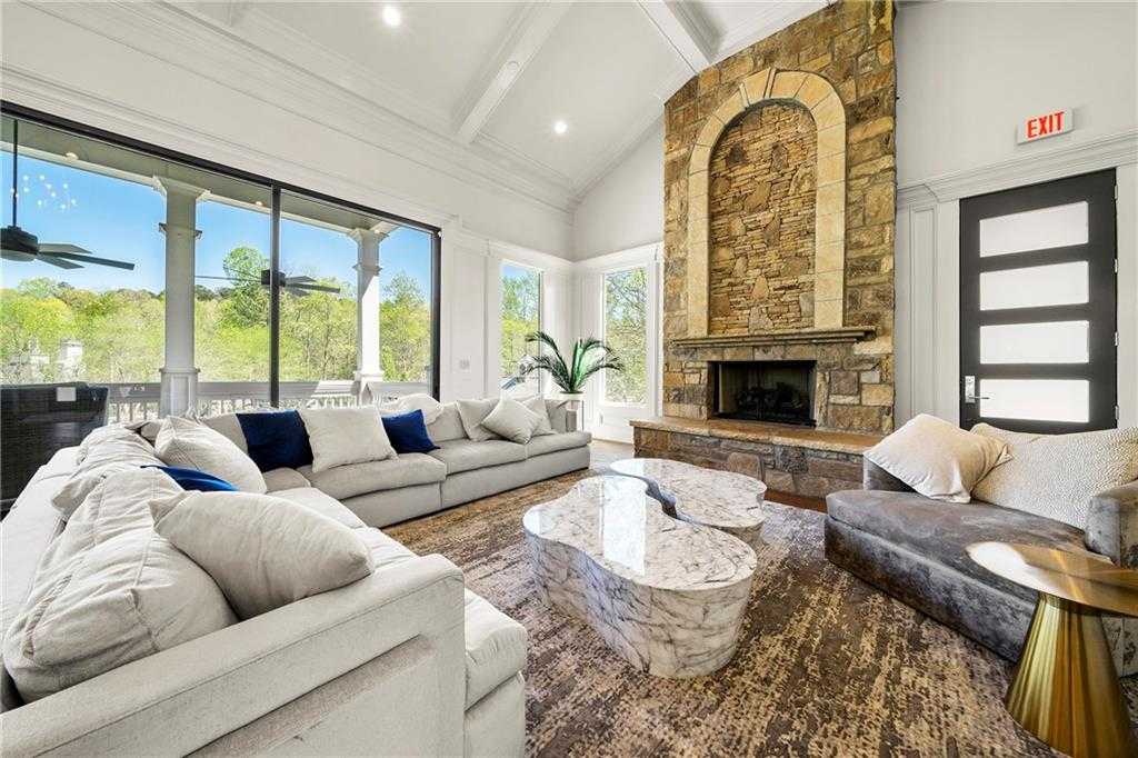 Spacious living room with arched stone fireplace, gray sectionals, and large windows in Davidson Homes The Ash B- Unfinished Basement, Riverwood, Dallas, Georgia