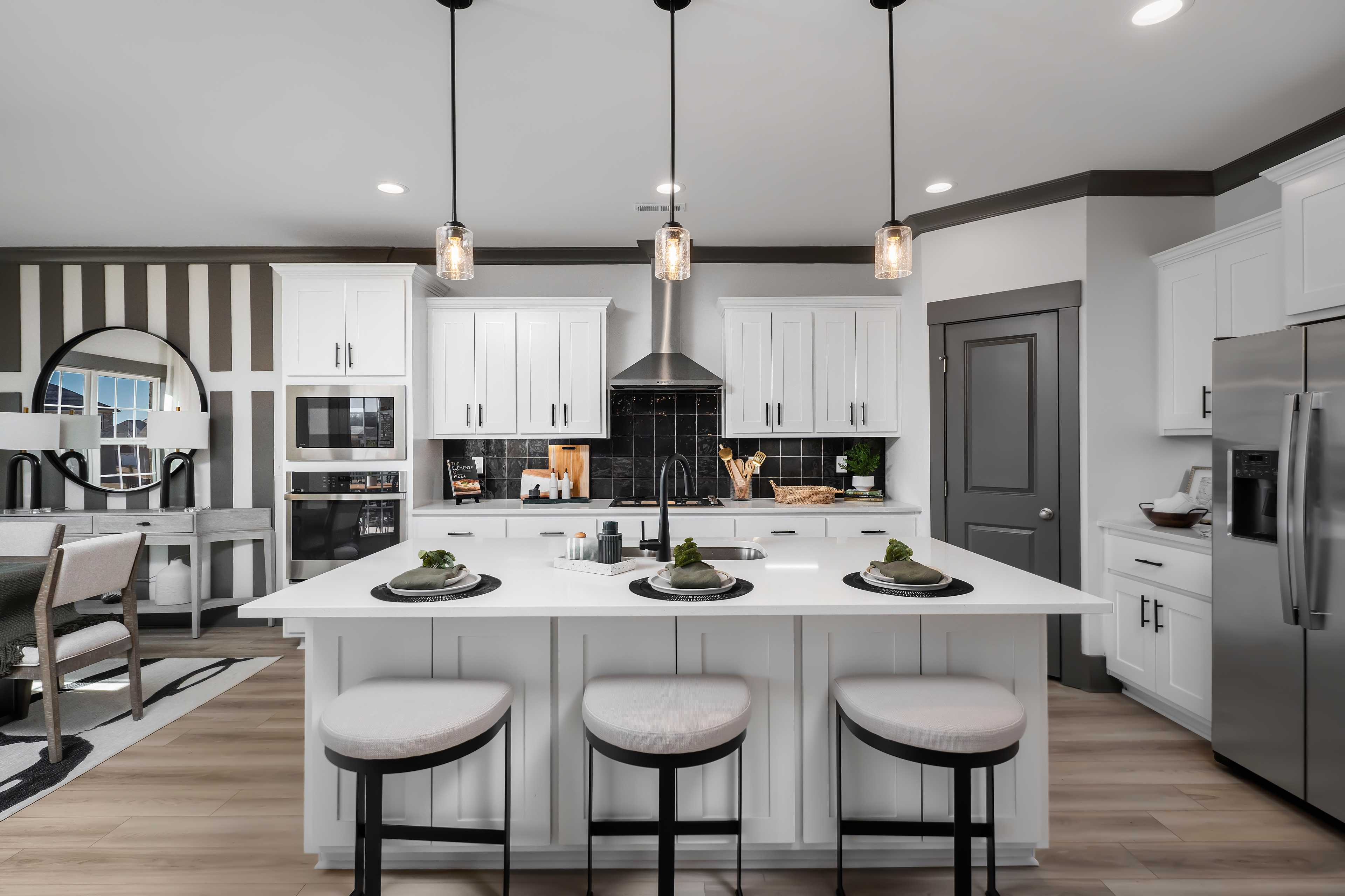 Spacious white kitchen at Barnett's Crossing in Madison AL with island bar stools, stainless appliances, and pendant lights