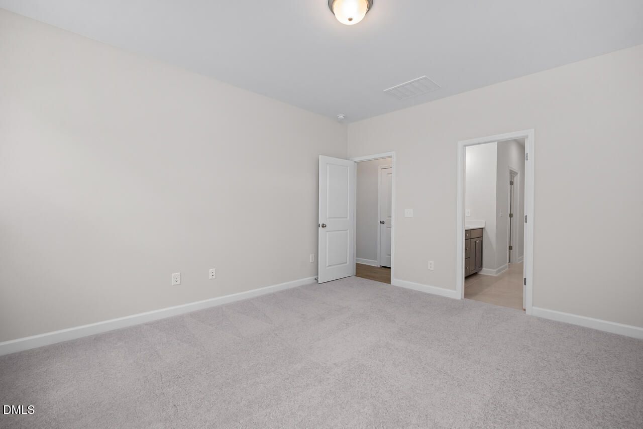 Spacious bedroom with plush carpet and en-suite bathroom in The Ashport G floor plan at Sage on North Main, Wake Forest.