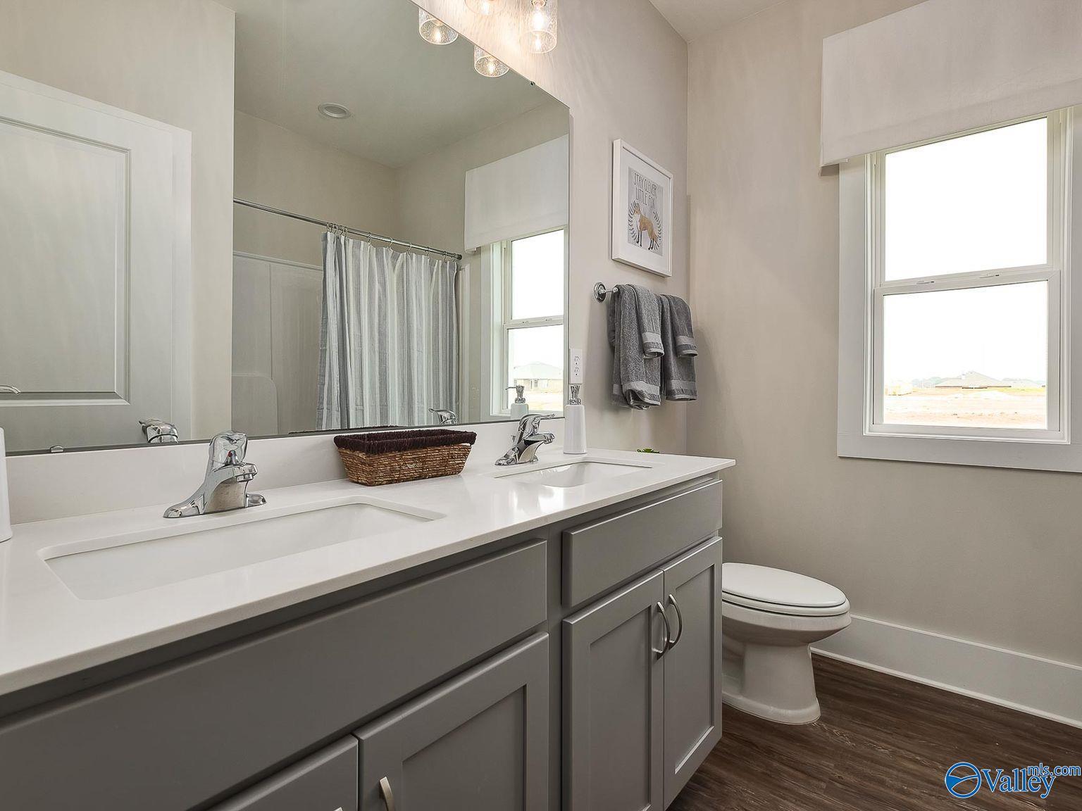 Modern bathroom with double vanity, gray shaker cabinets, and frameless shower in Davidson Homes The Everett, Toney, AL