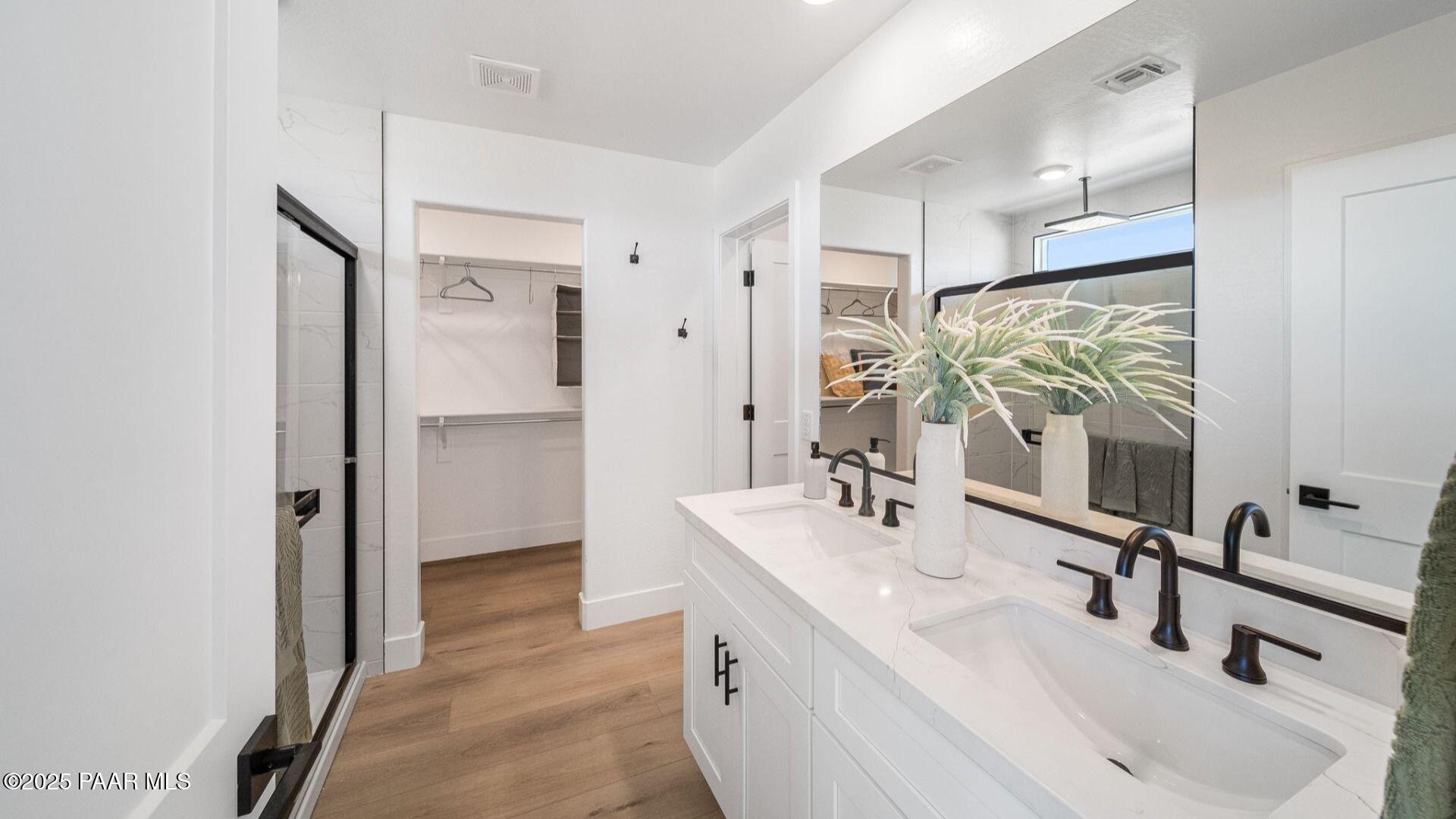 Modern master bathroom featuring double white vanity, black faucets, walk-in closet, and glass shower in Davidson Homes The Wilmington B, Prescott, AZ