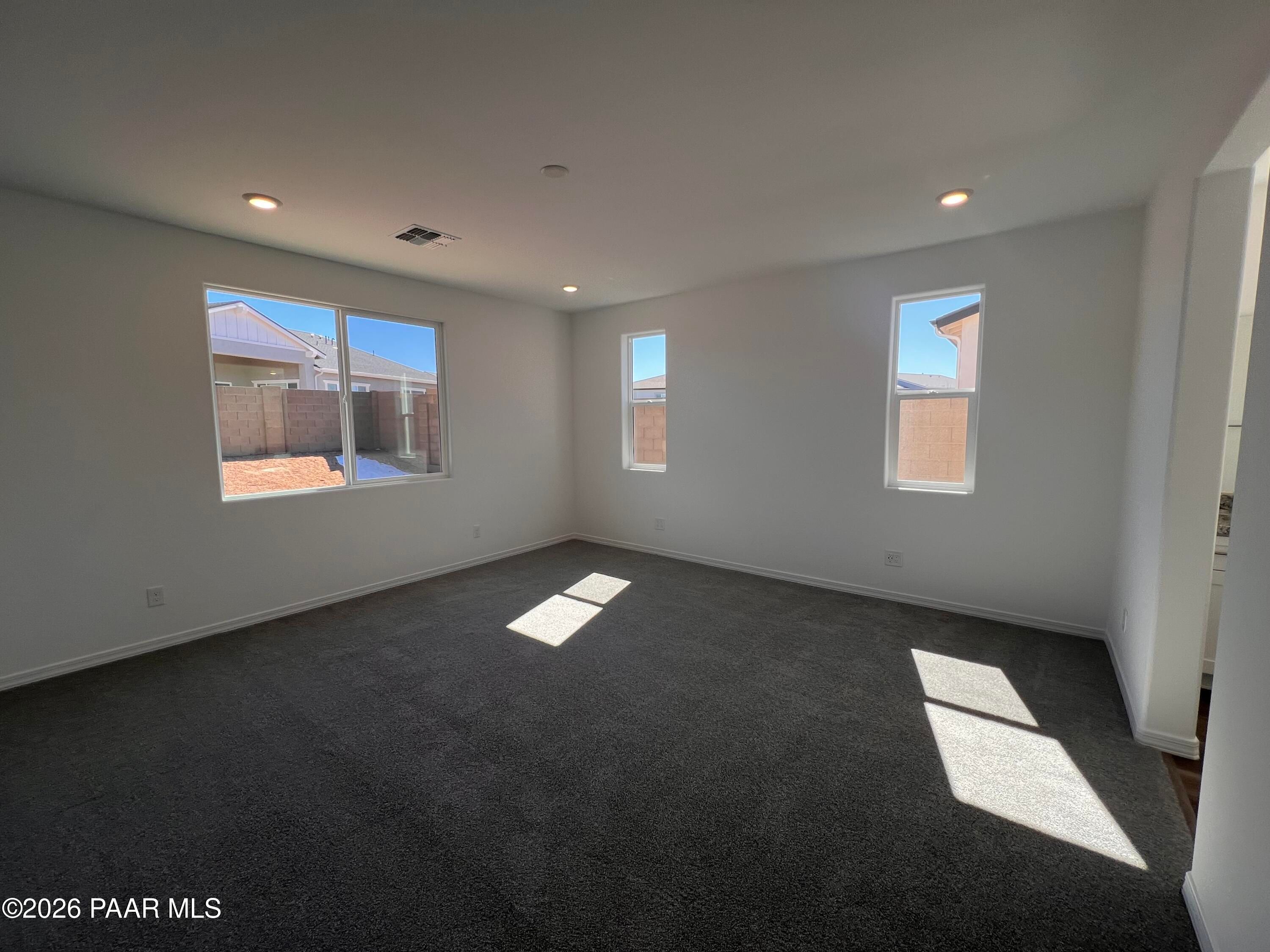 Bright living room with large sunny windows, white walls, and plush carpet in Davidson Homes Sunrise II A, Prescott AZ