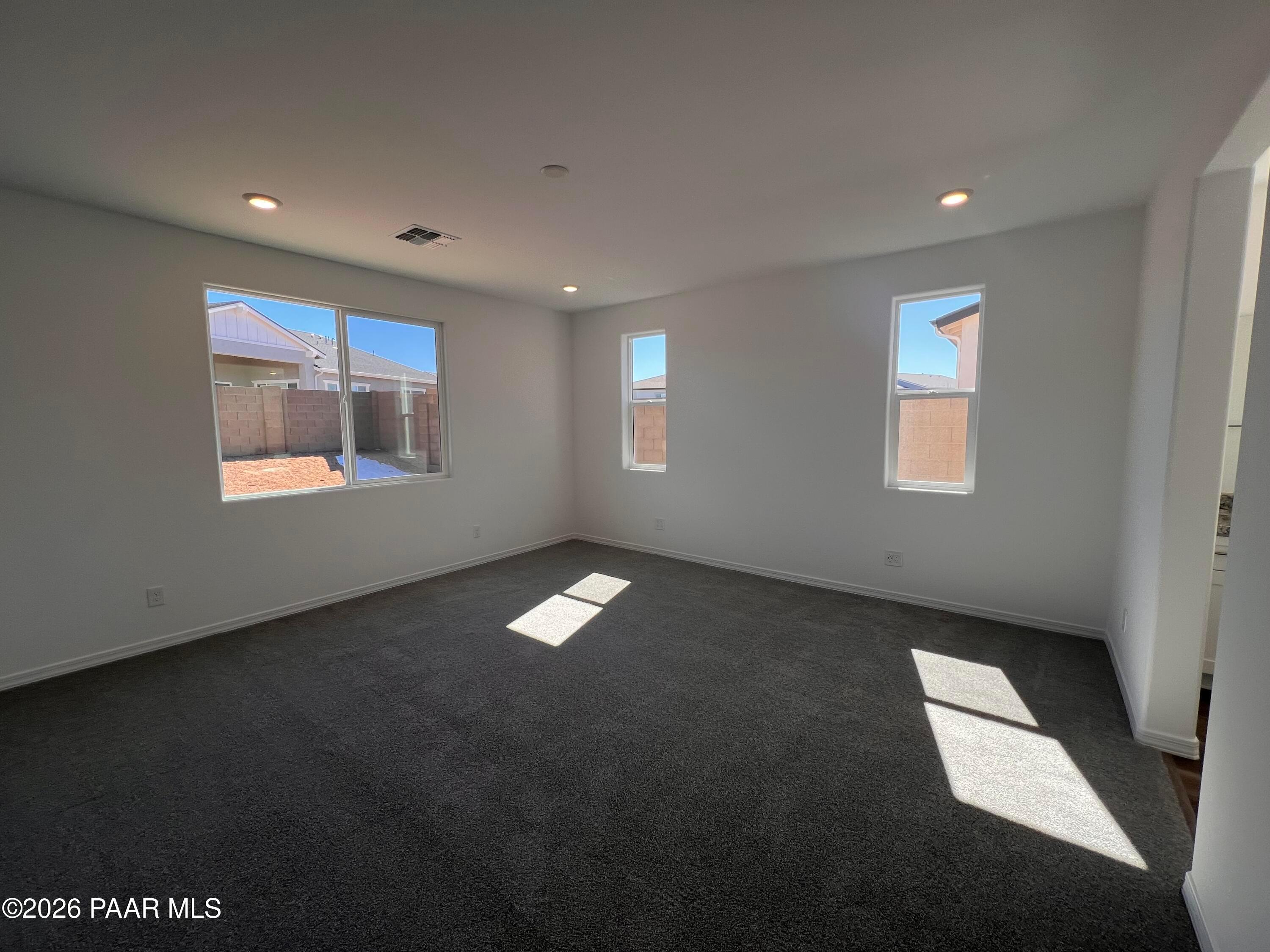 Bright living room with large sunny windows, white walls, and plush carpet in Davidson Homes Sunrise II A, Prescott AZ