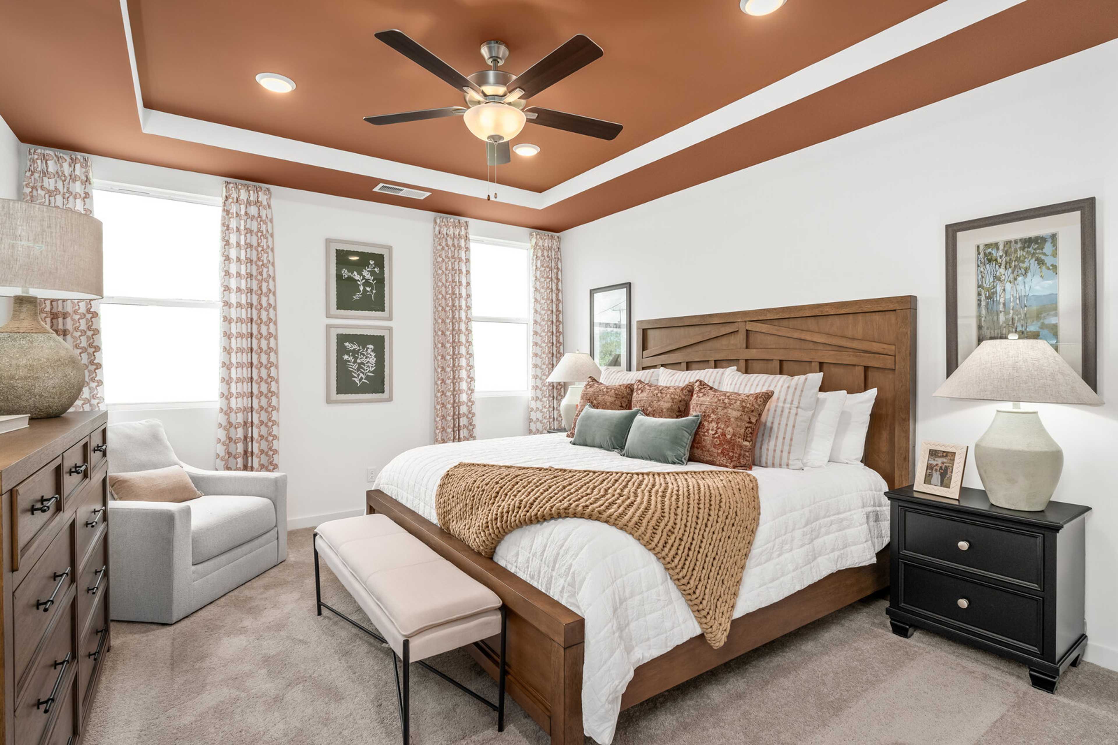 Spacious master bedroom at Calista Farms in White House TN with wooden bed frame, neutral linens, ceiling fan and sheer curtains