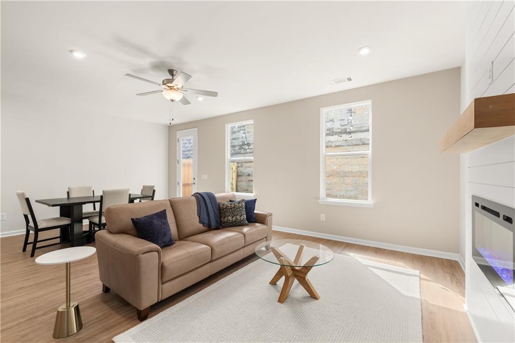 Cozy living room with leather sofa, modern fireplace, ceiling fan, and dining area in Davidson Homes The Marion B, Kennesaw, Georgia