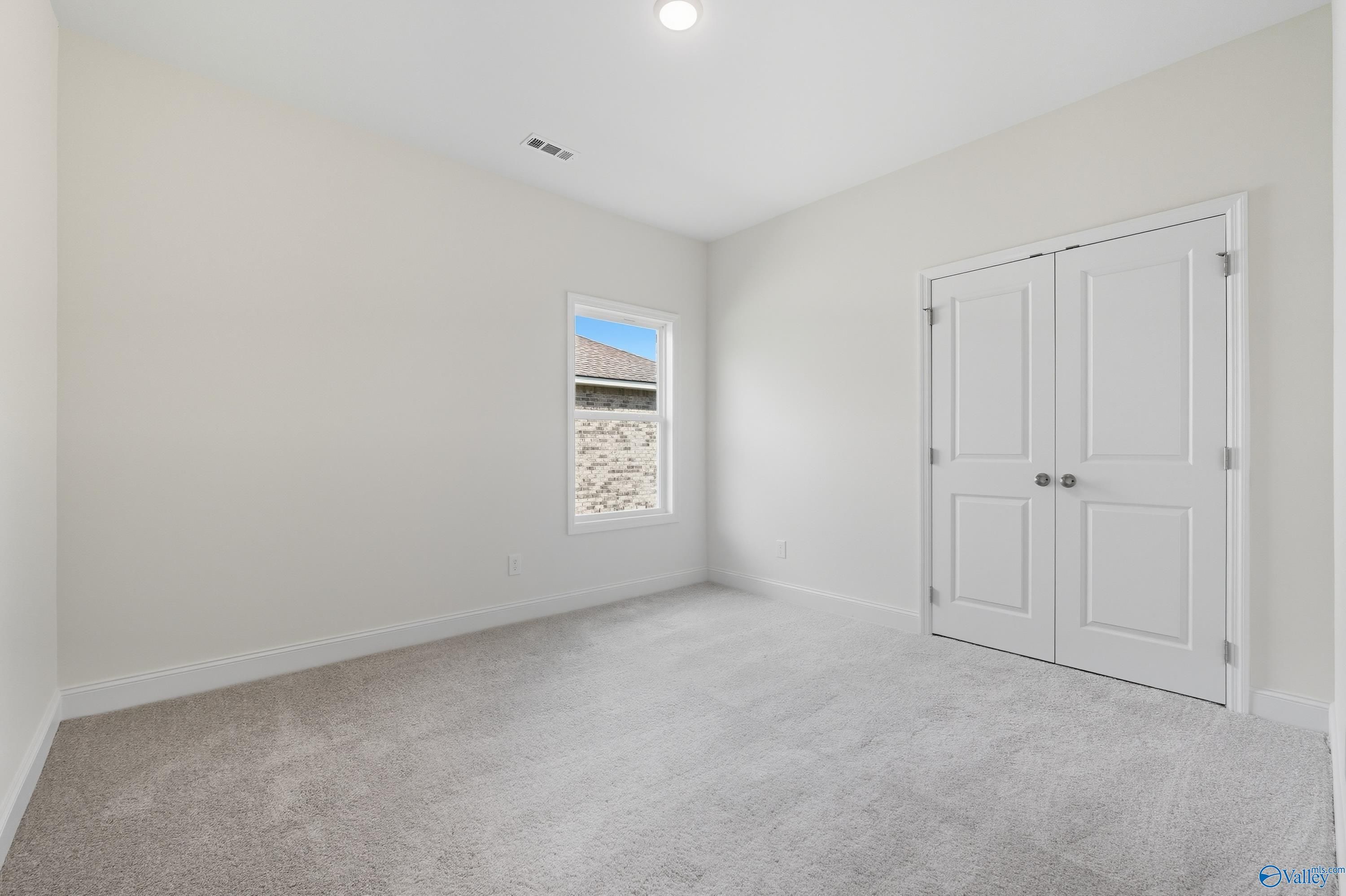 Bright secondary bedroom with large window and double-door closet in Davidson Homes The Everett, Meridianville, Alabama