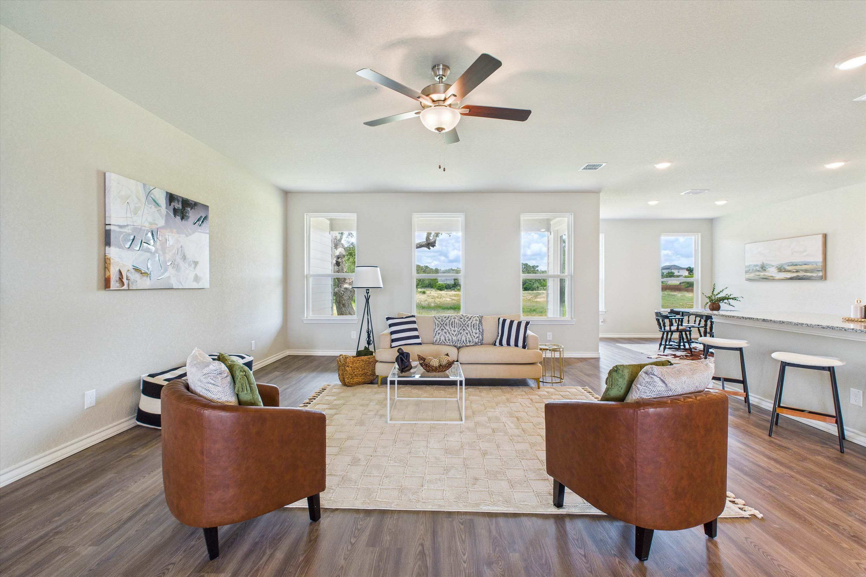 Open-concept living room in The Foster floor plan featuring leather armchairs, modern furniture, and a spacious layout.