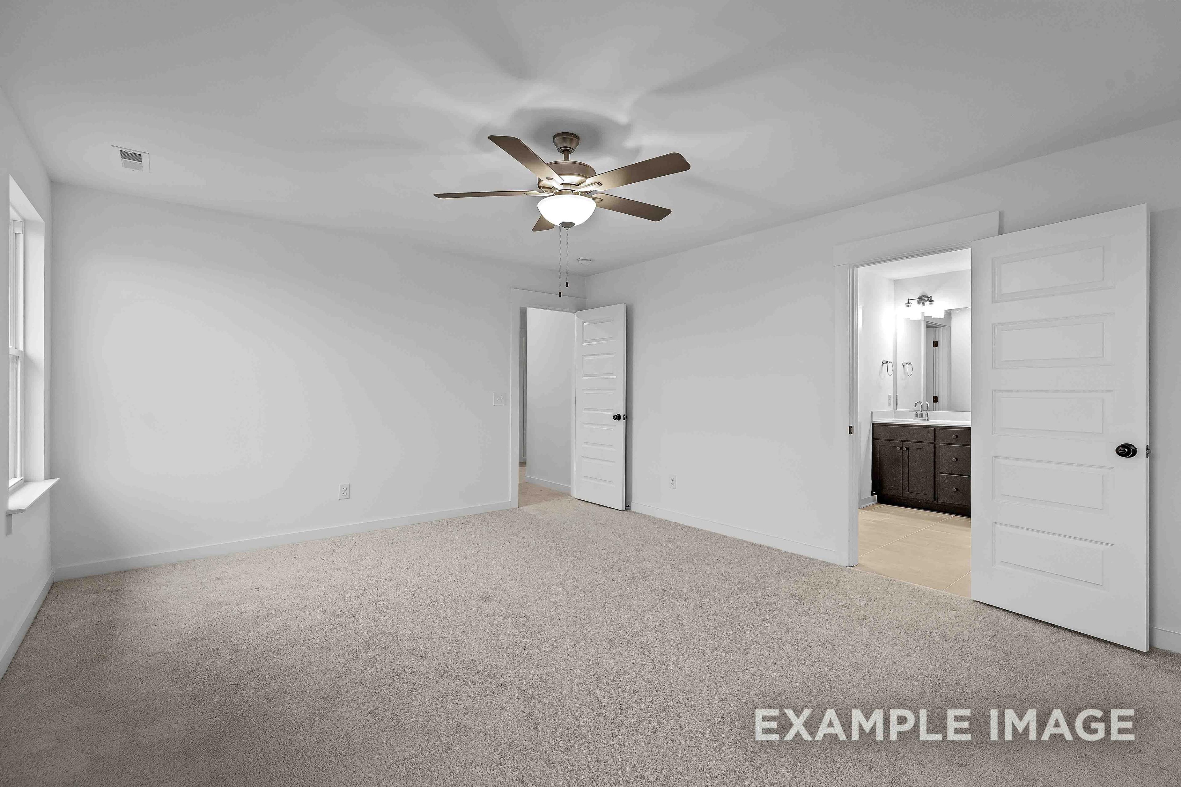 The Charleston master bedroom showcasing ceiling fan, neutral walls, carpet flooring, and en-suite bathroom vanity