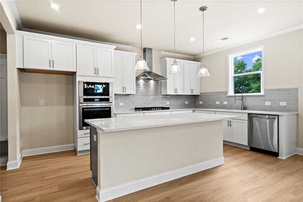 Spacious modern kitchen with white shaker cabinets, quartz island, stainless appliances in Davidson Homes The Hickory B at Wehunt Meadows, Hoschton
