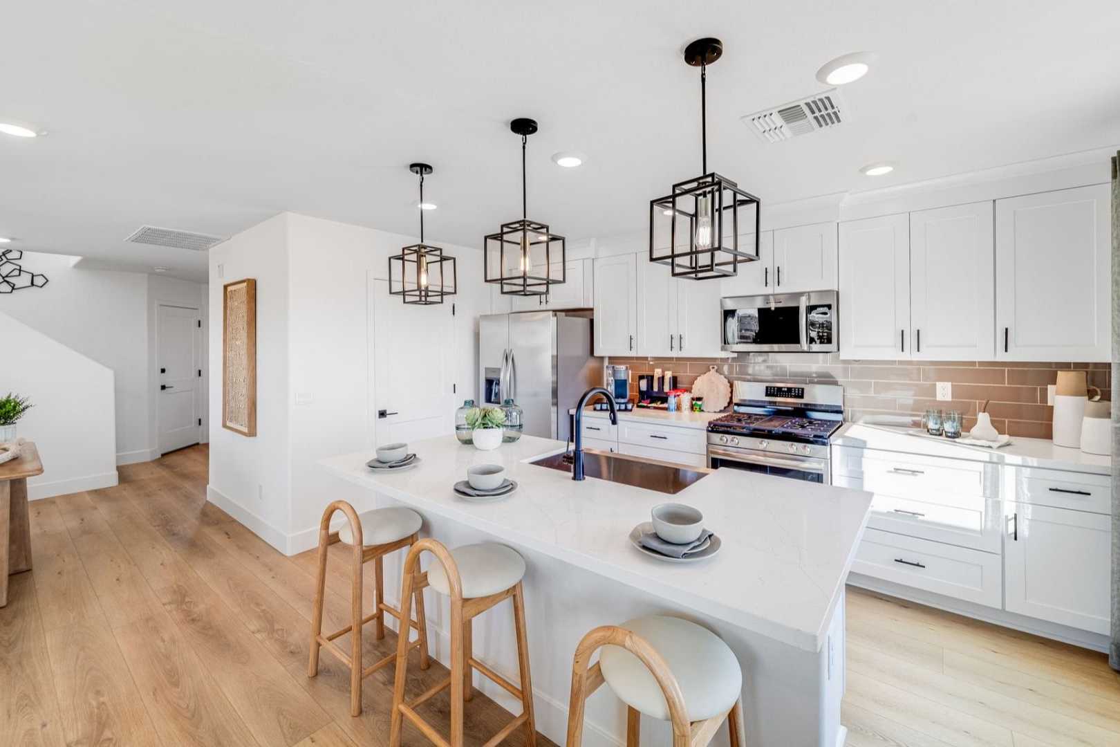 Spacious open-concept kitchen with white island, pendant lights, and hardwood floors at South Ranch Southern Collection in Prescott AZ