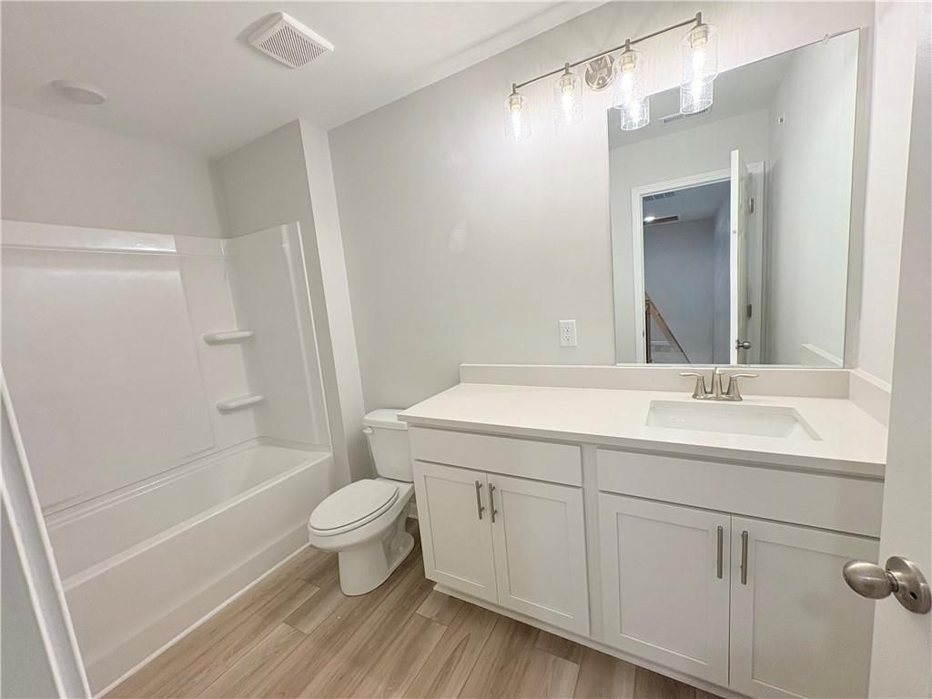 Modern guest bathroom with white vanity, soaking tub, luxury vinyl plank flooring in The Wake E, Cumming, Georgia