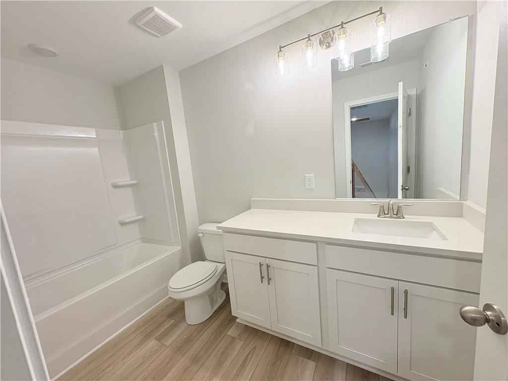 Modern guest bathroom with white vanity, soaking tub, luxury vinyl plank flooring in The Wake E, Cumming, Georgia