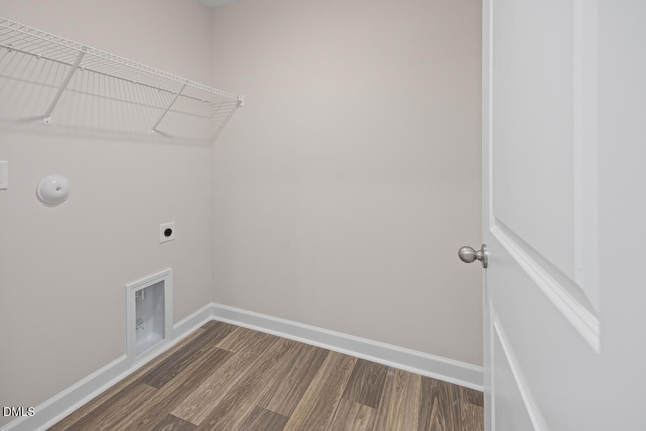 Laundry room with white wire shelving and wood-look flooring in The Graham floor plan at Springvale, Fuquay-Varina, NC.