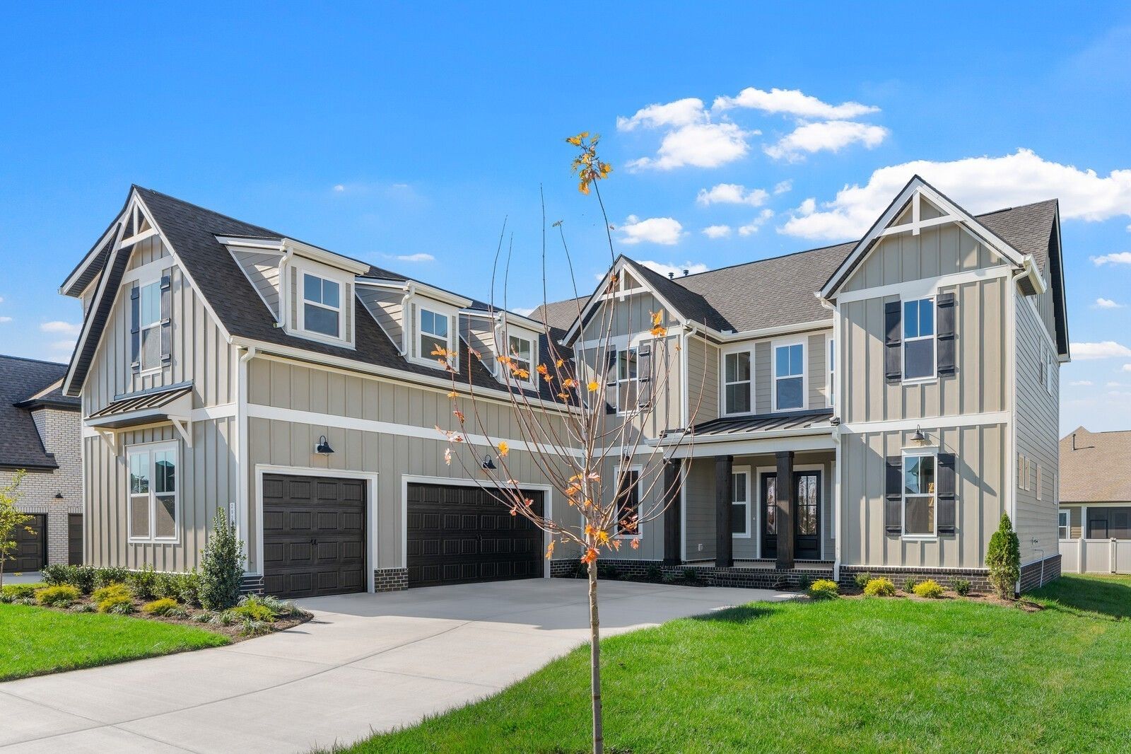 Two-story beige Davidson Homes The Alston A with 3-car garage, driveway, and autumn tree in Shelton Square, Murfreesboro, Tennessee