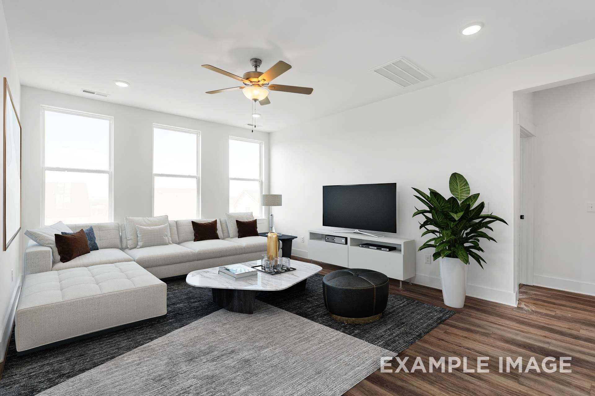 Spacious living room in The Ash home design with white L-shaped sofa, TV console, large windows, and potted plant